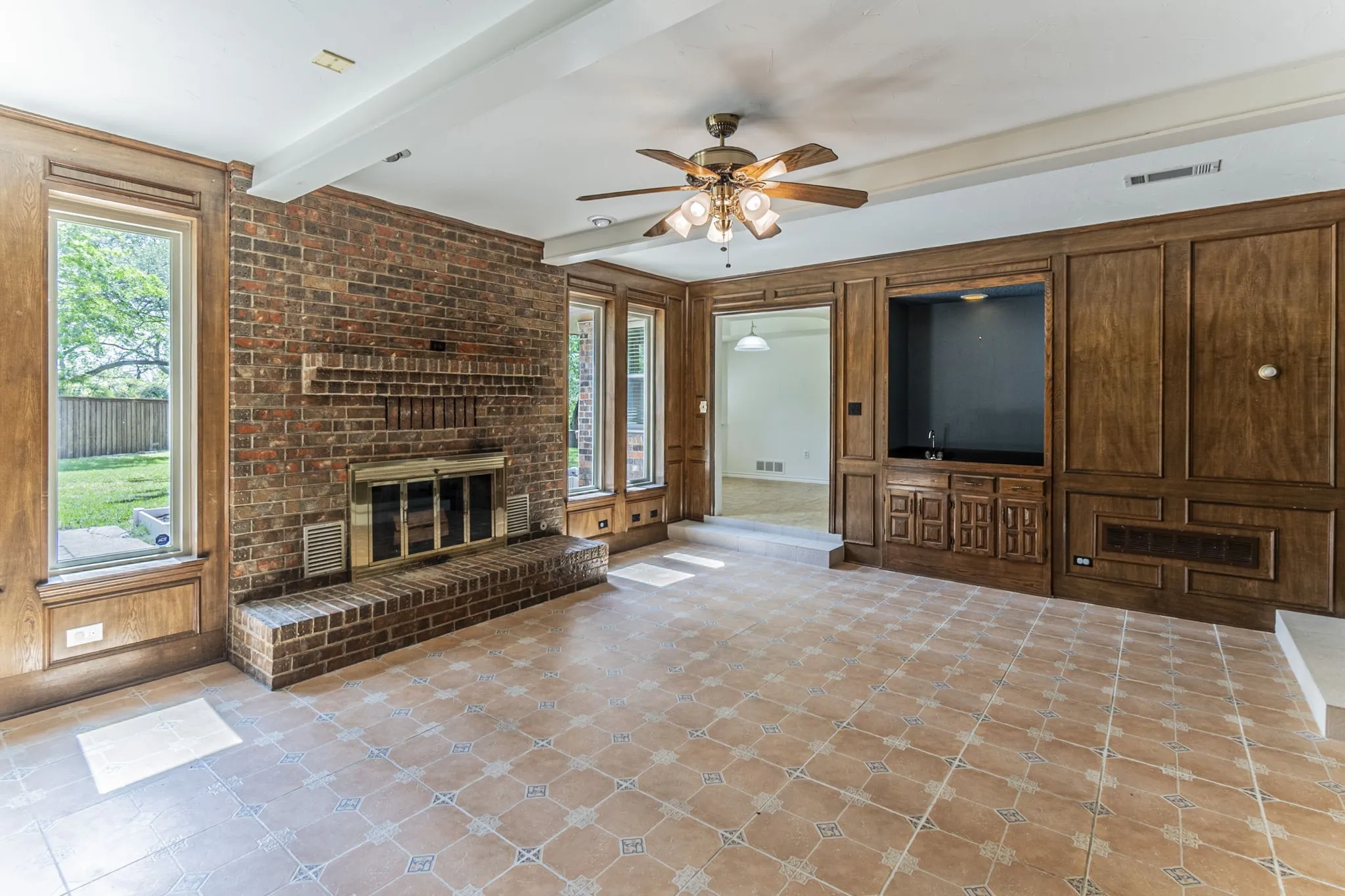 Unfurnished living room featuring a fireplace, ceiling fan, and beam ceiling