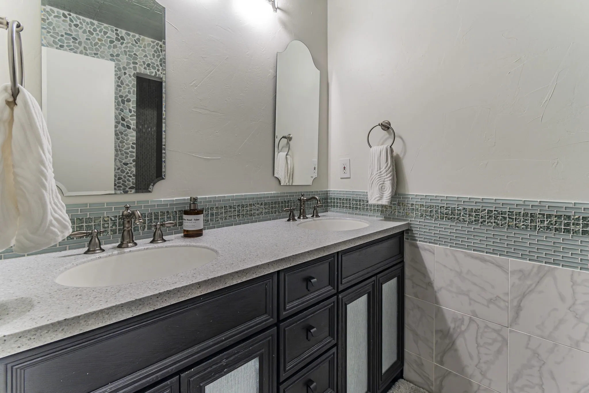 Full bathroom featuring double vanity, tile walls, and wainscoting