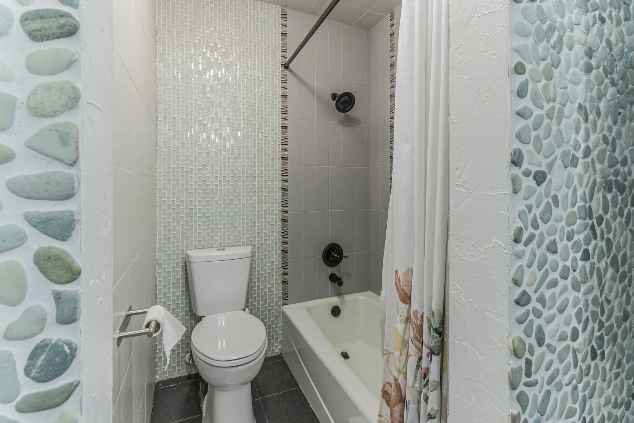 Full bath featuring shower / bathtub combination with curtain, dark tile patterned floors, and tile walls