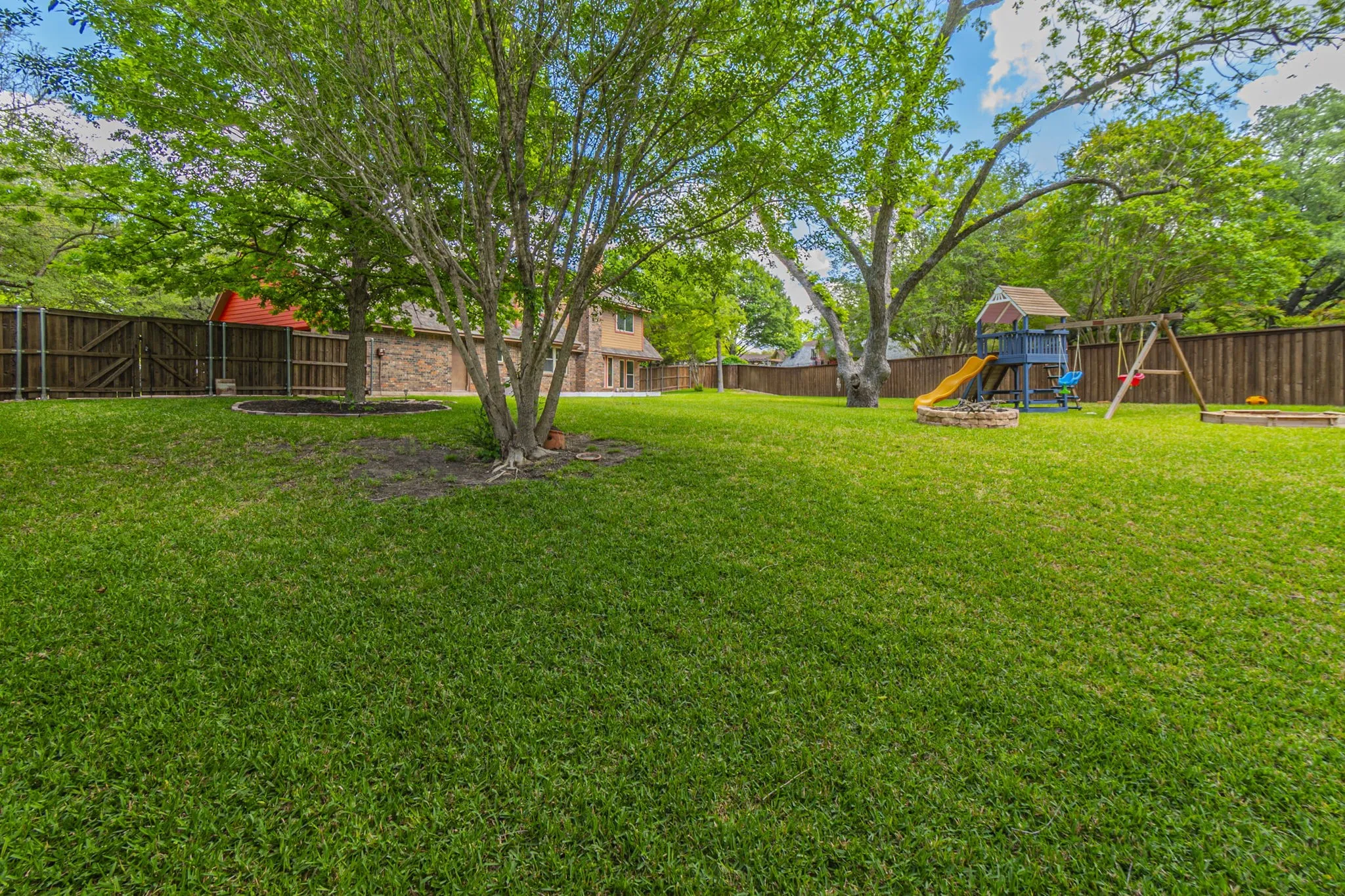 Fenced backyard featuring a playground