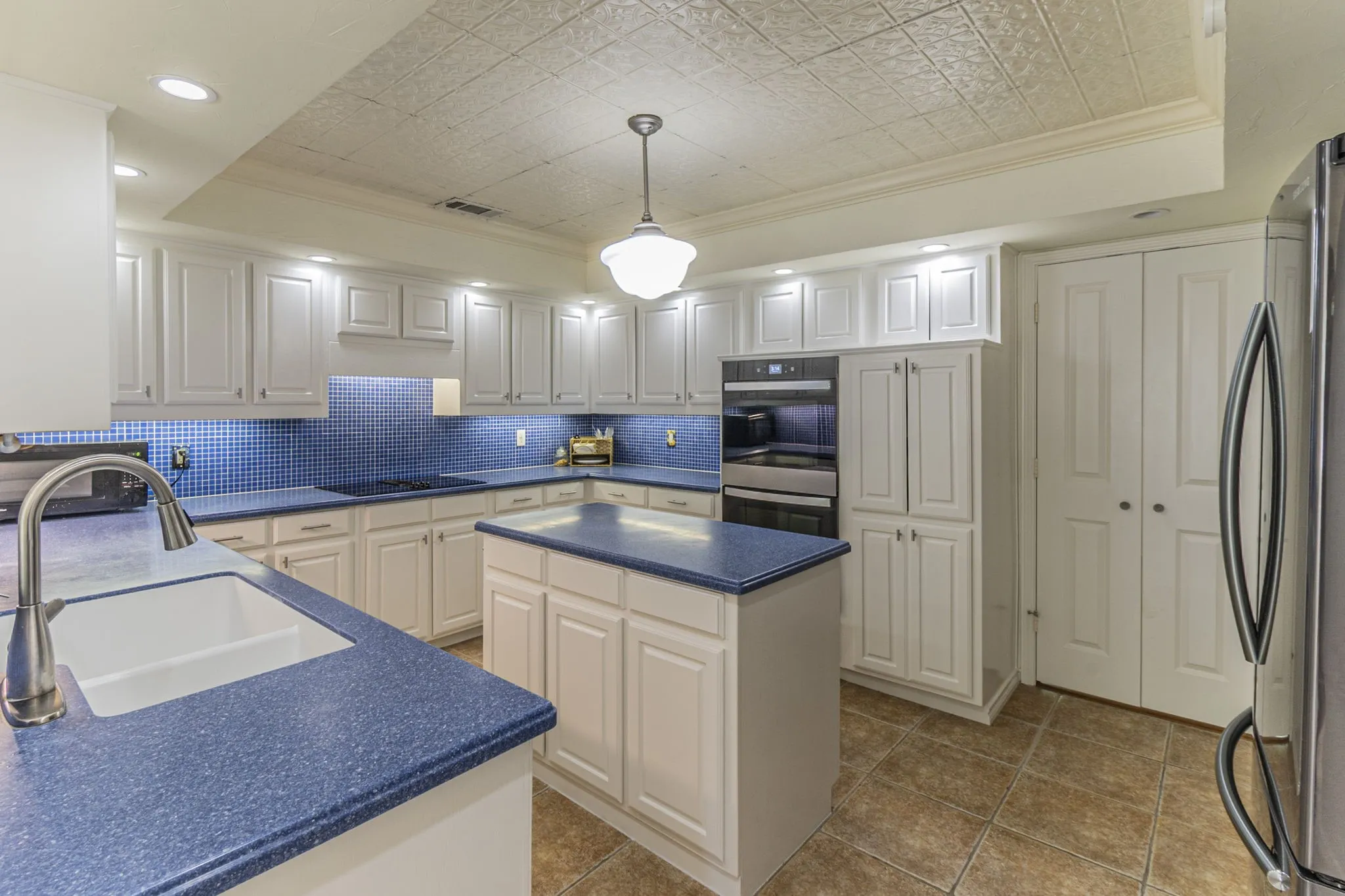 Kitchen featuring ornamental molding, an ornate ceiling, dark countertops, freestanding refrigerator, and a raised ceiling