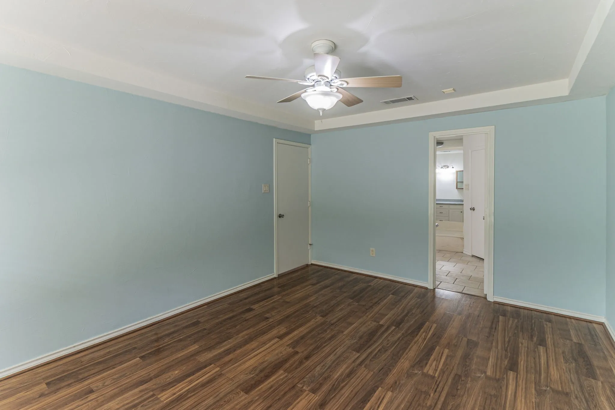 Unfurnished bedroom with dark wood-type flooring, a ceiling fan, and ensuite bath