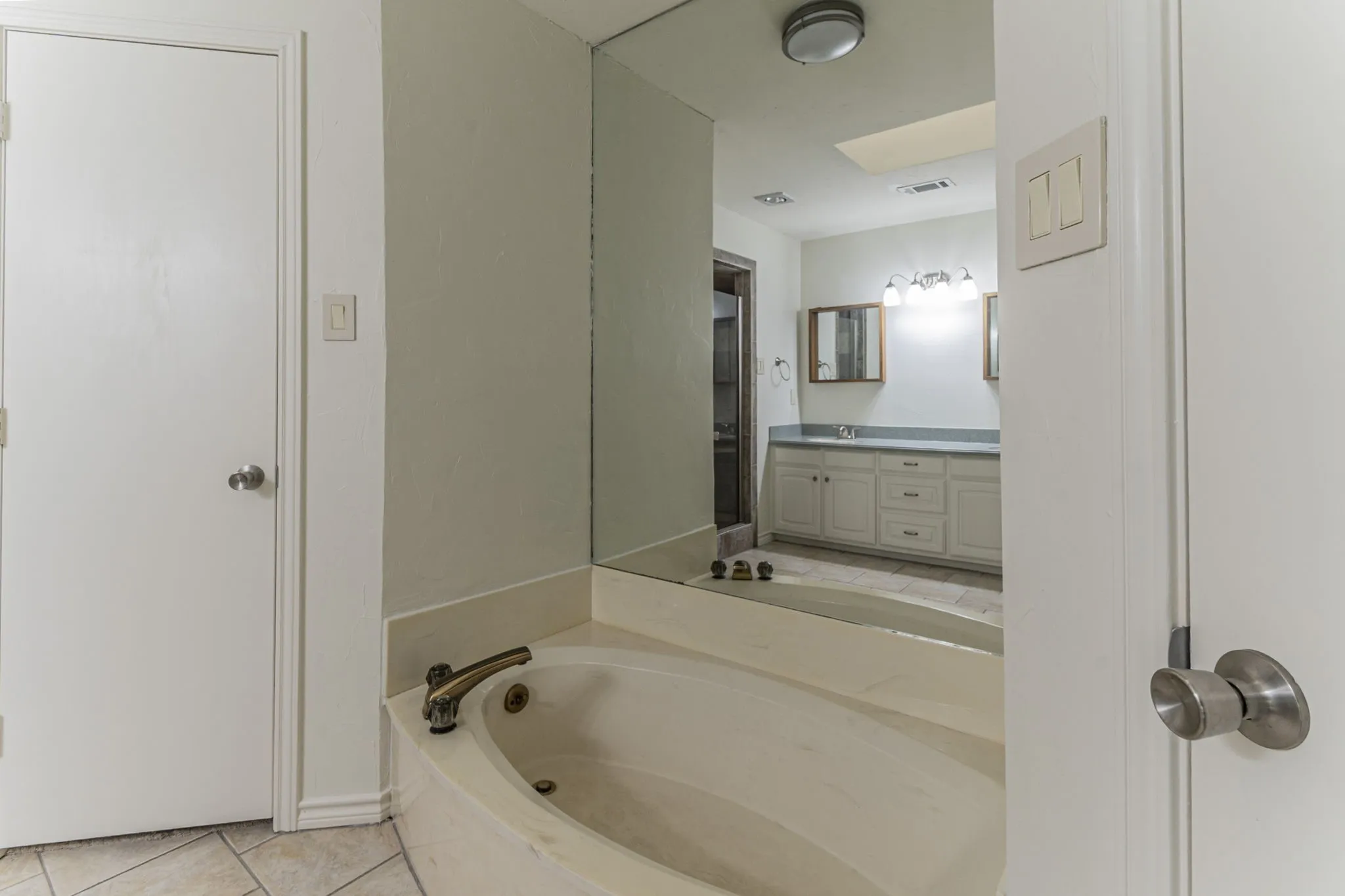 Full bathroom featuring double vanity, light tile patterned flooring, and a garden tub