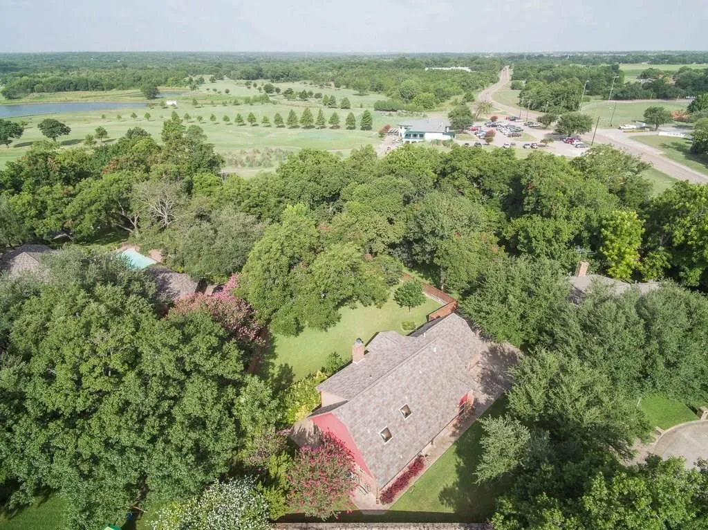 Aerial property view featuring a red brick structure with a dark shingle roof and multiple skylights