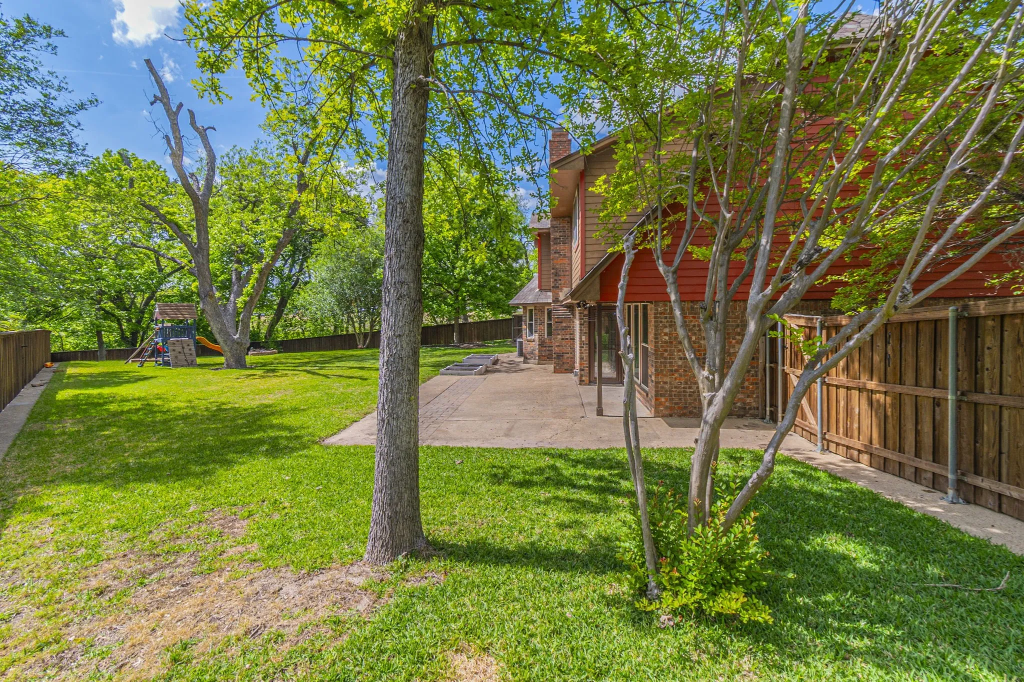 Fenced backyard featuring a patio and a playground