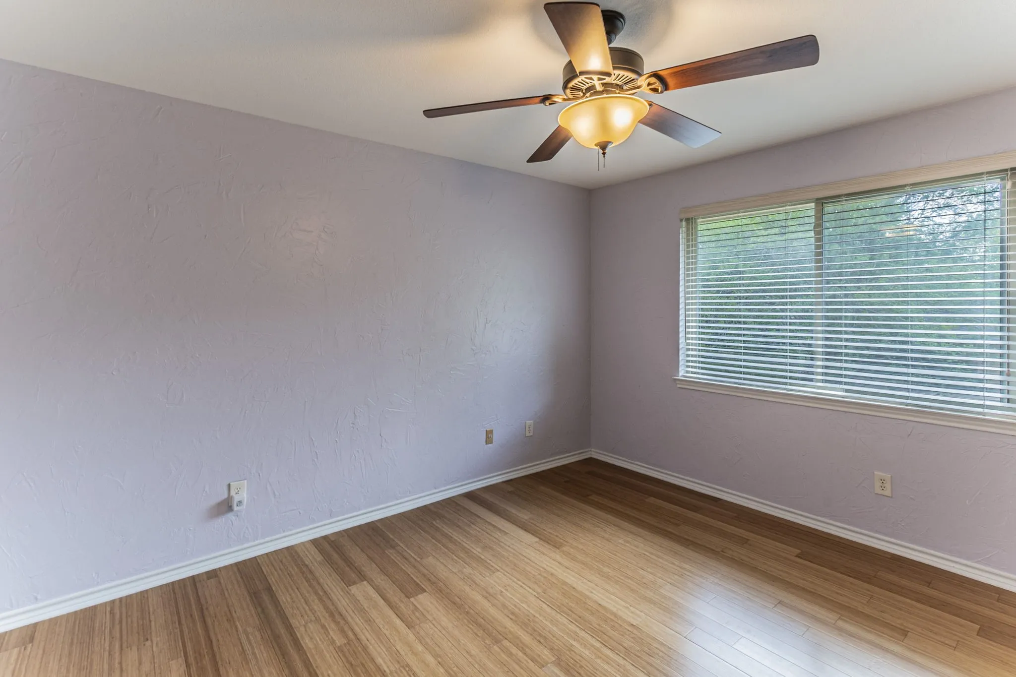 Unfurnished room featuring a ceiling fan, light wood-type flooring, and a textured wall