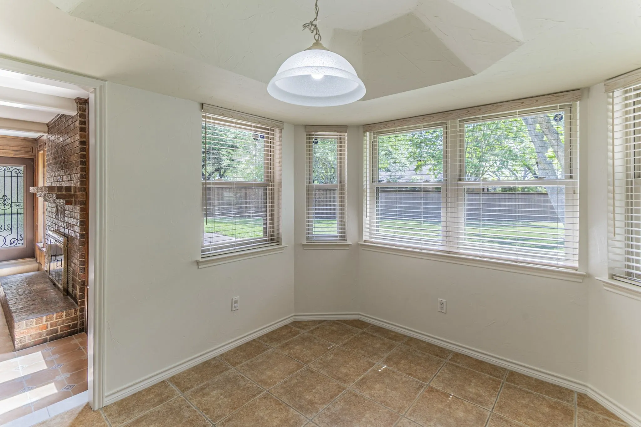 Unfurnished dining area with plenty of natural light, brick wall, a fireplace, and light tile patterned floors