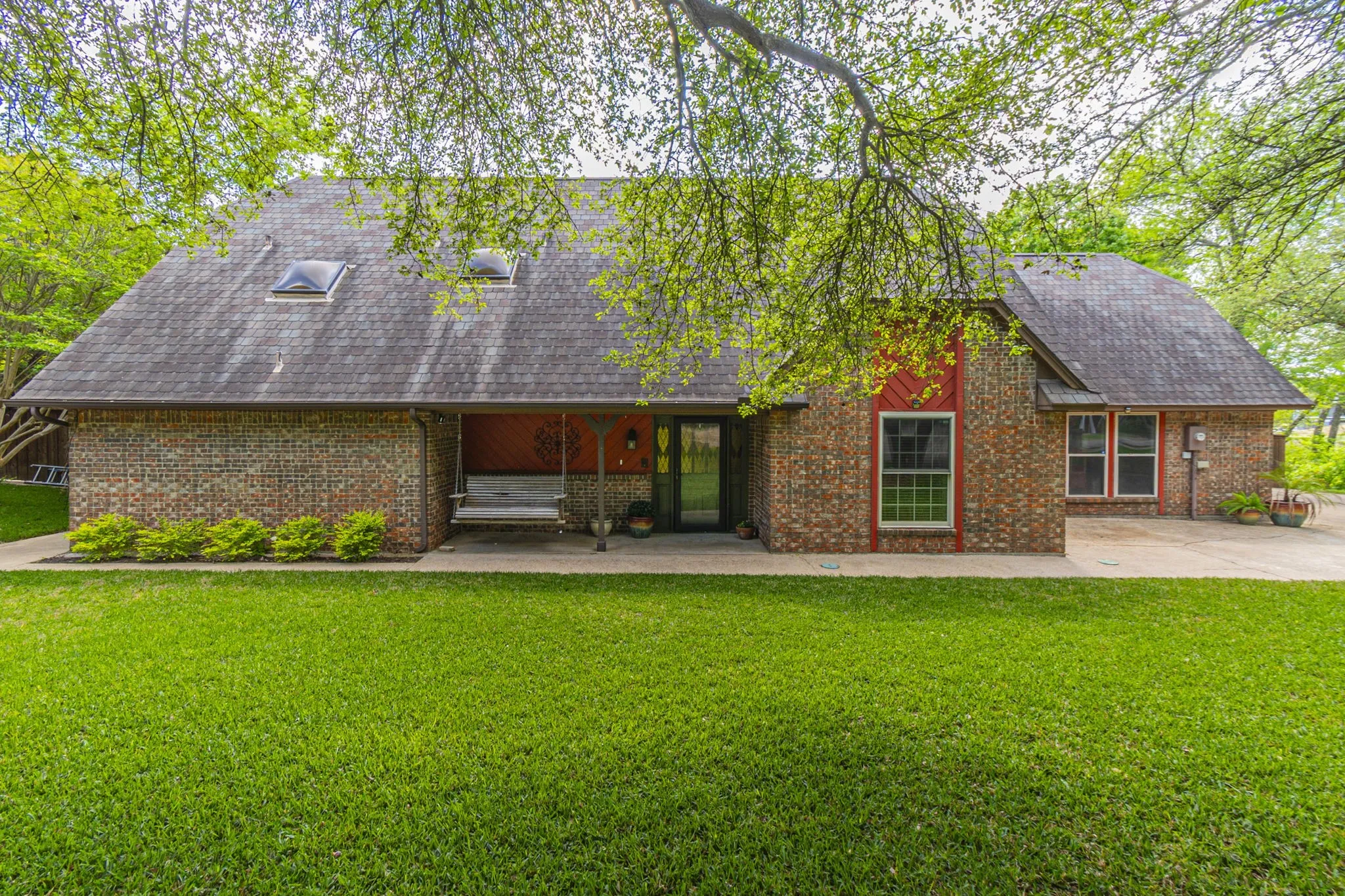 Back of house with a lawn, roof with shingles, and brick siding