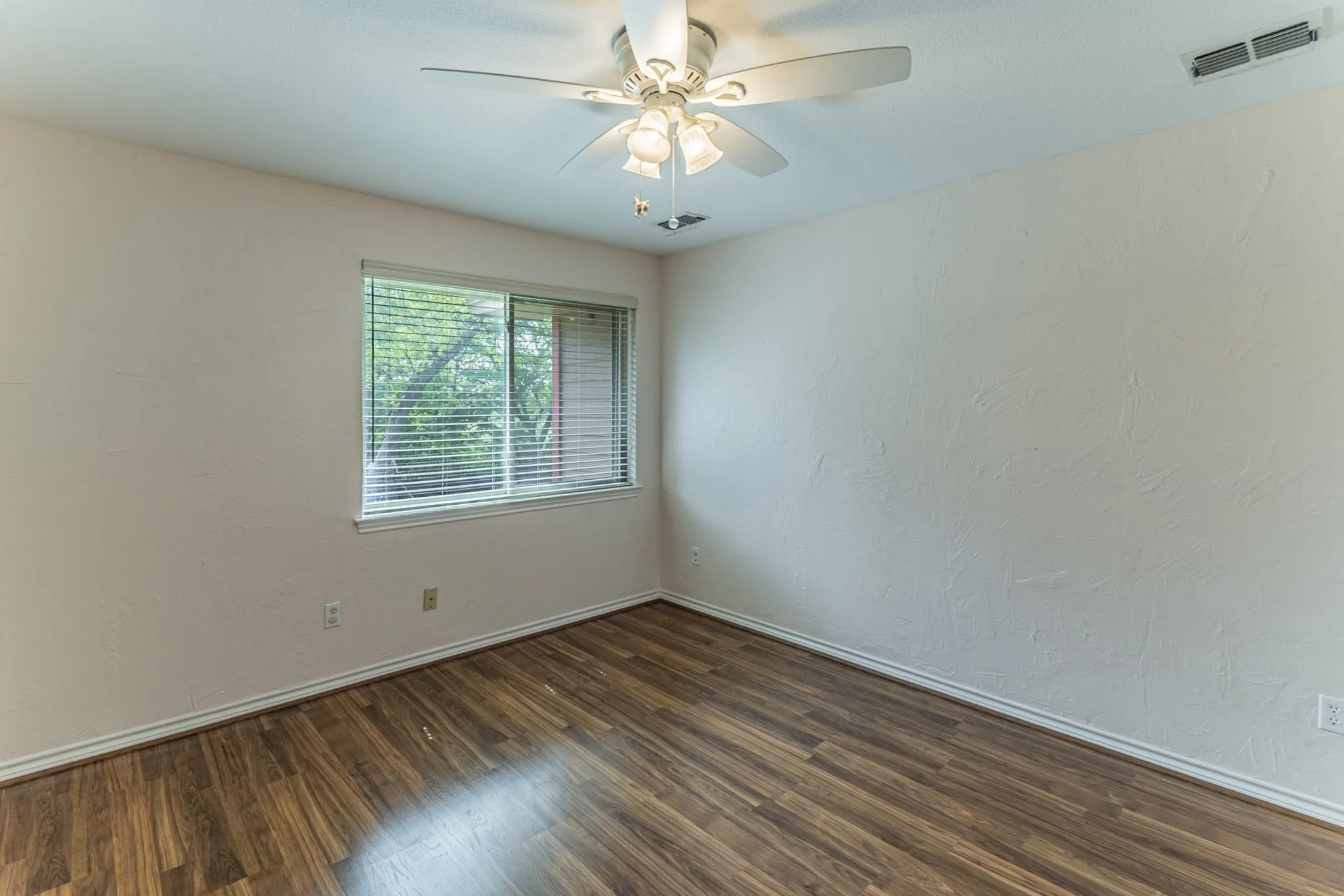 Spare room with ceiling fan, dark wood-type flooring, and a textured wall