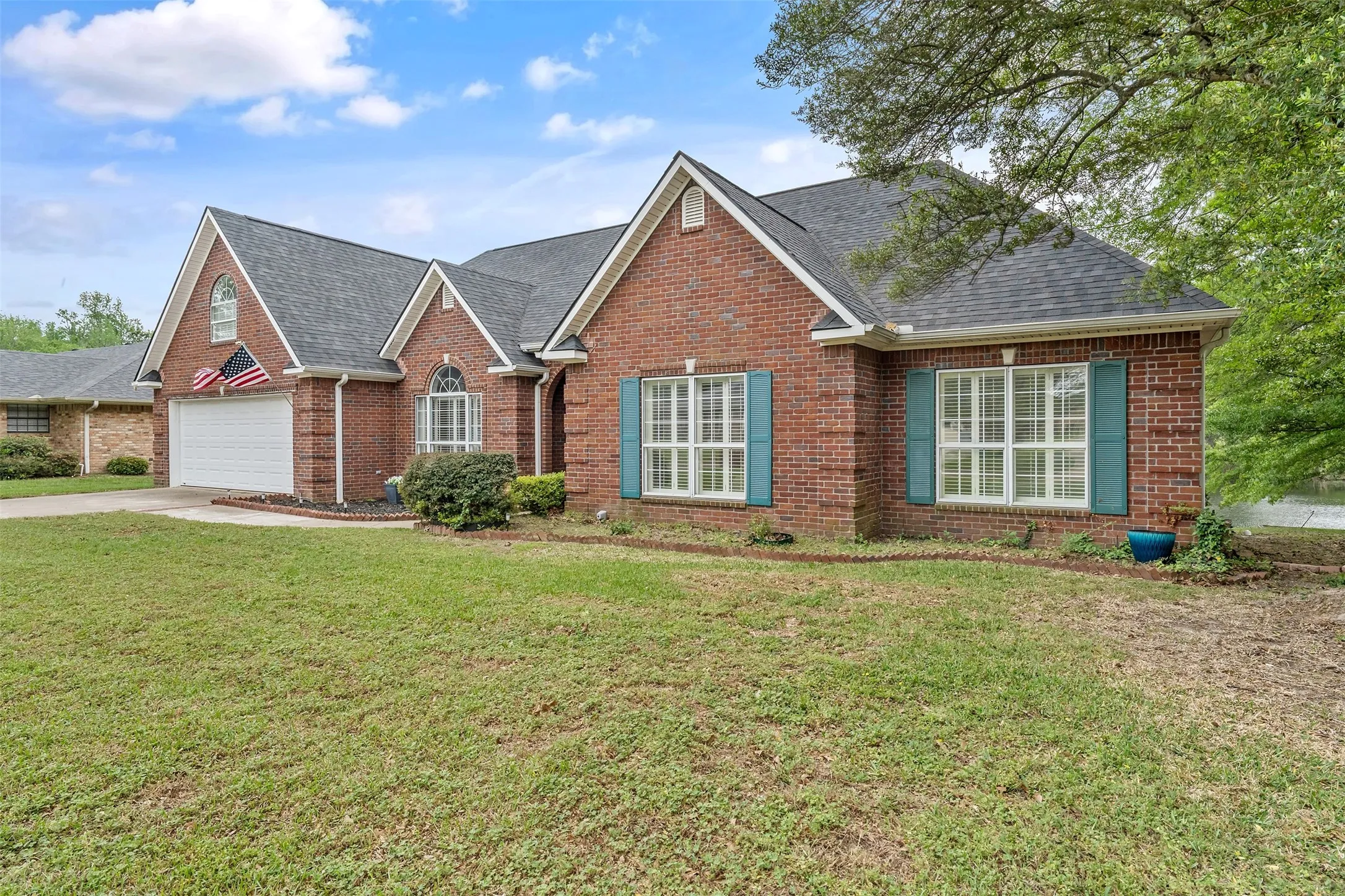 View of front of house featuring brick siding, a front lawn, and roof with shingles