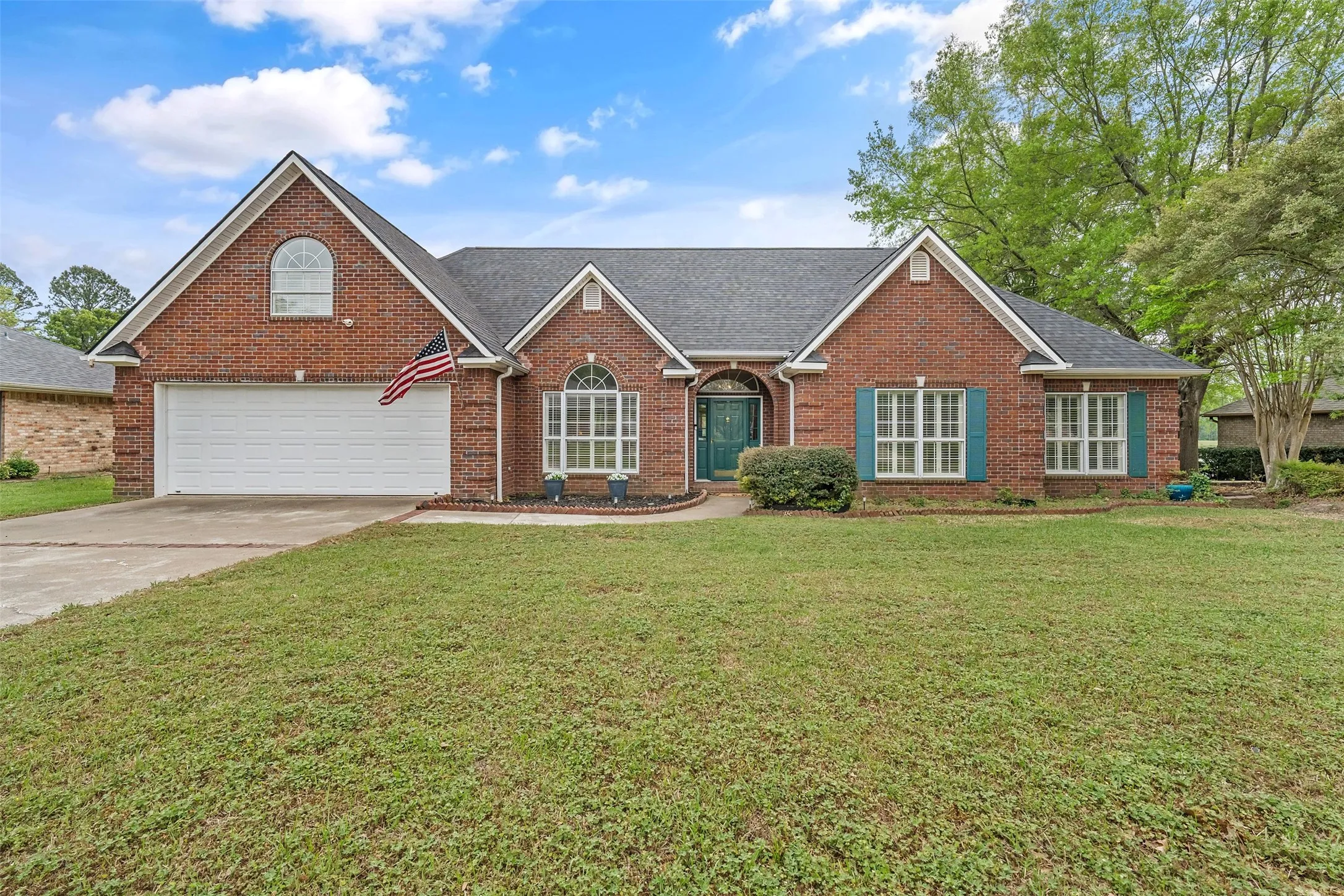 View of front of house with brick siding, a front yard, roof with shingles, concrete driveway, and a garage