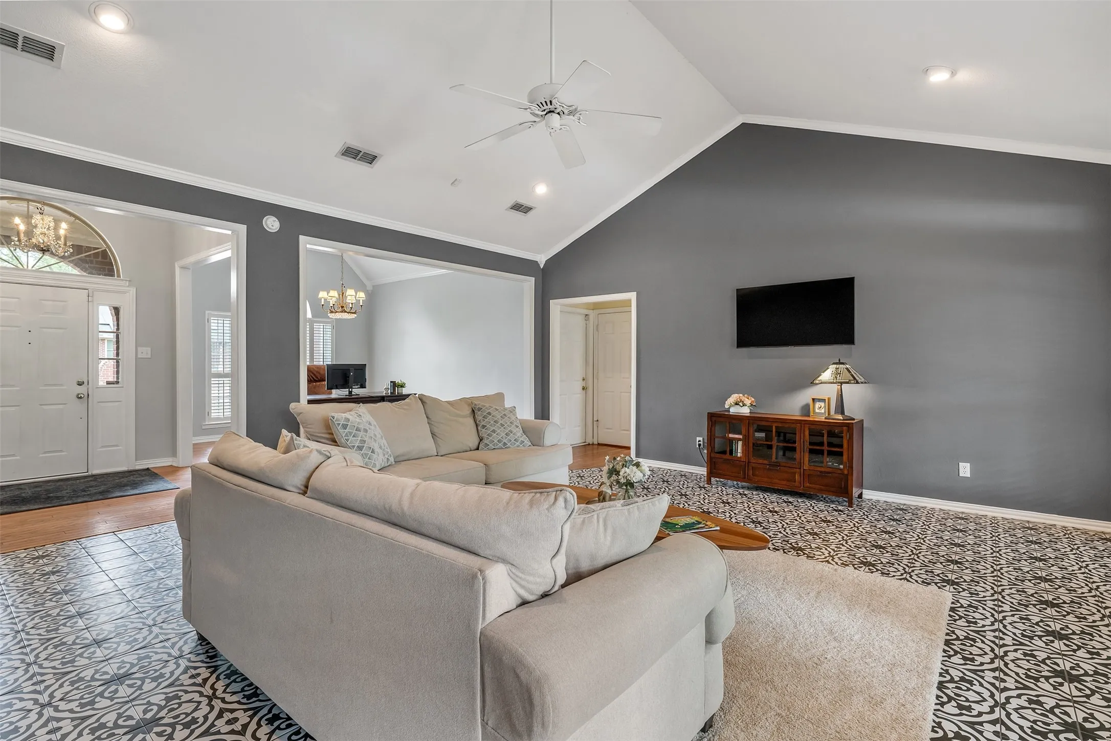 Living area with suspended lighting, ceiling fan, crown molding, and a high ceiling