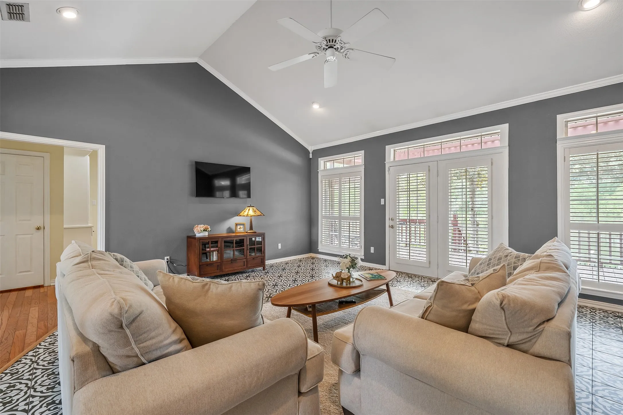 Living room featuring crown molding, ceiling fan, recessed lighting, wood finished floors, and a high ceiling