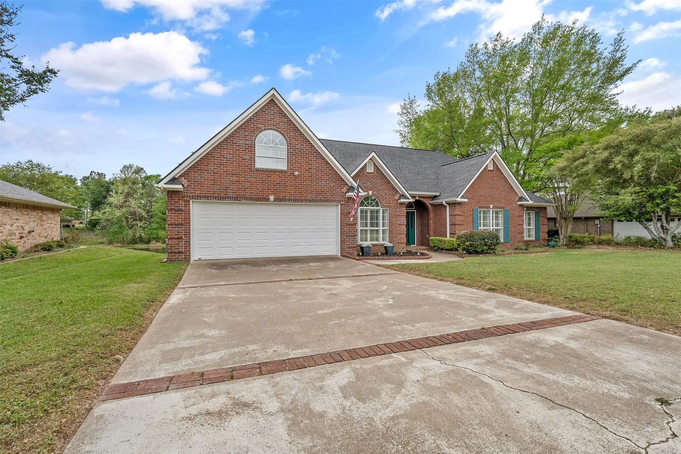 Traditional-style house featuring a front lawn, brick siding, driveway, a garage, and a shingled roof