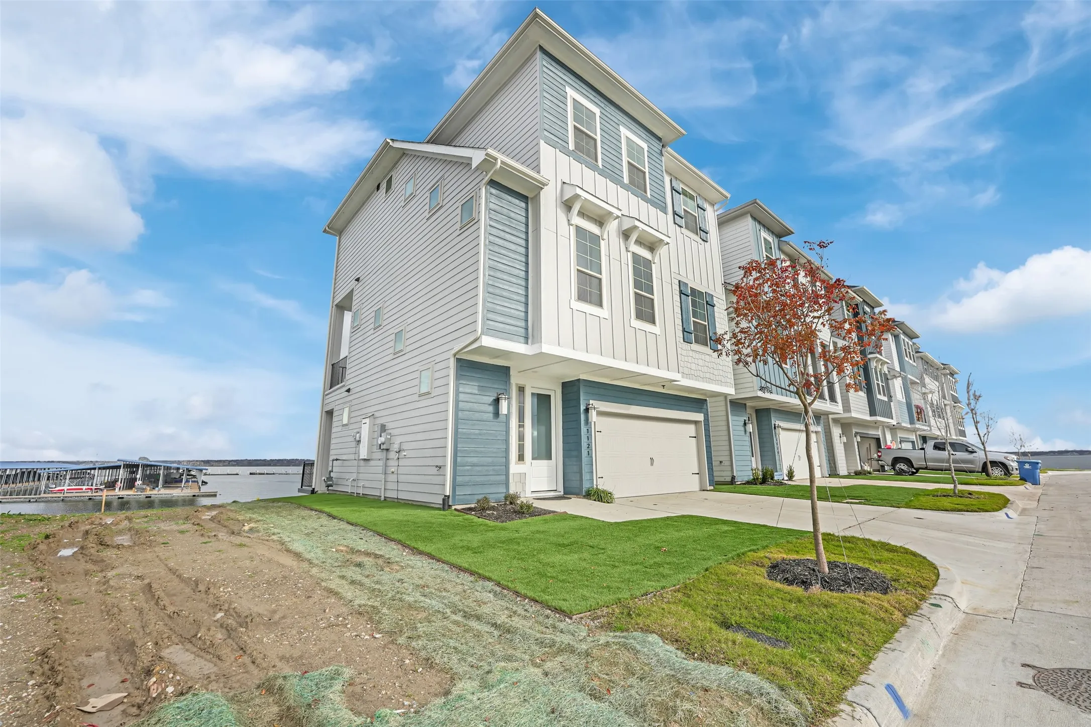 View of front of property with board and batten siding, concrete driveway, an attached garage, and a front lawn