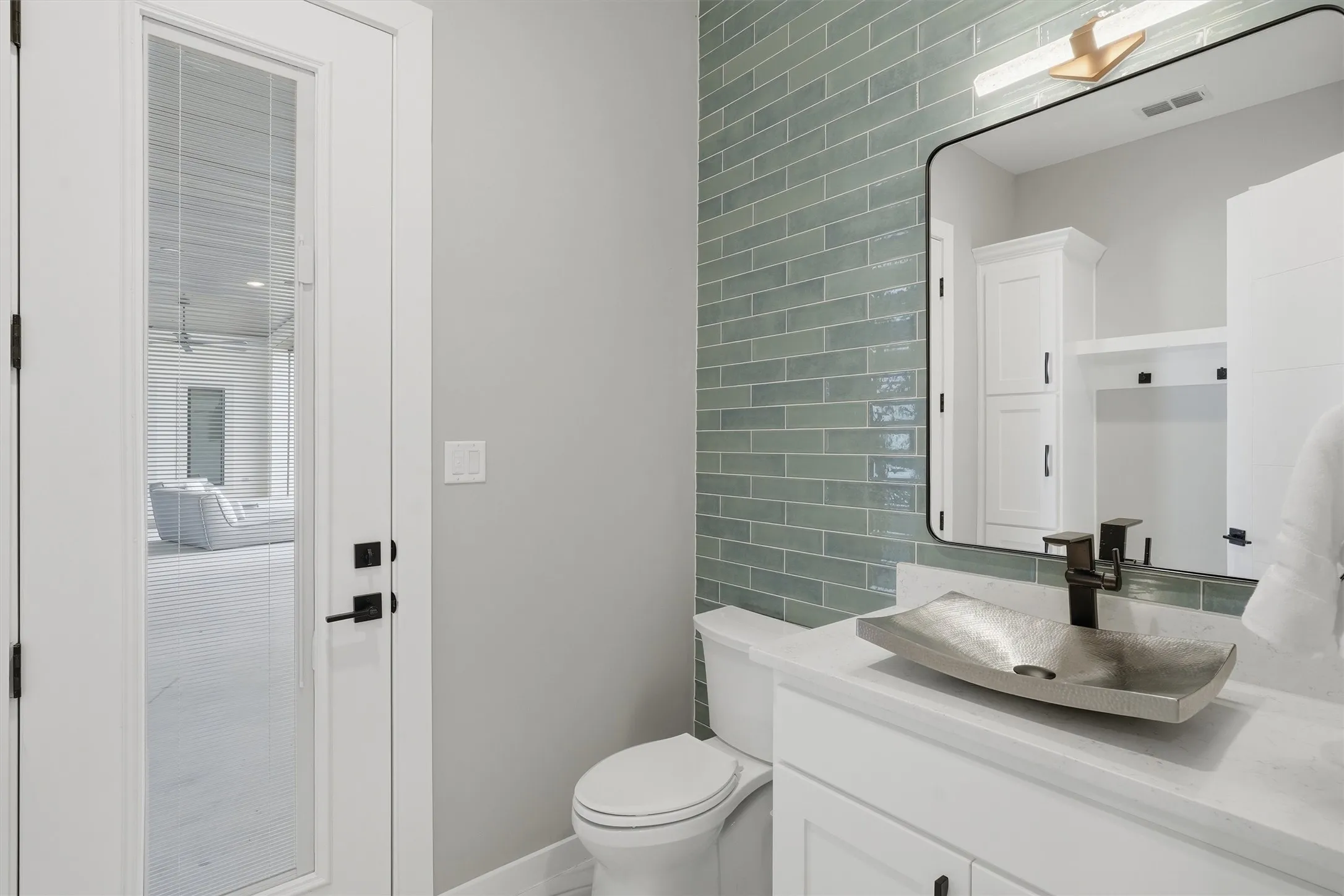 Pool bathroom with vanity and tile walls opens to the pool area