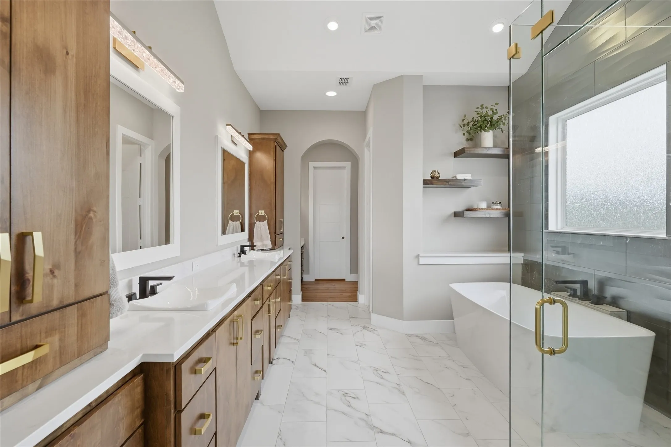 Bathroom featuring double vanity, a soaking tub, a shower stall, light marble finish floors, and recessed lighting