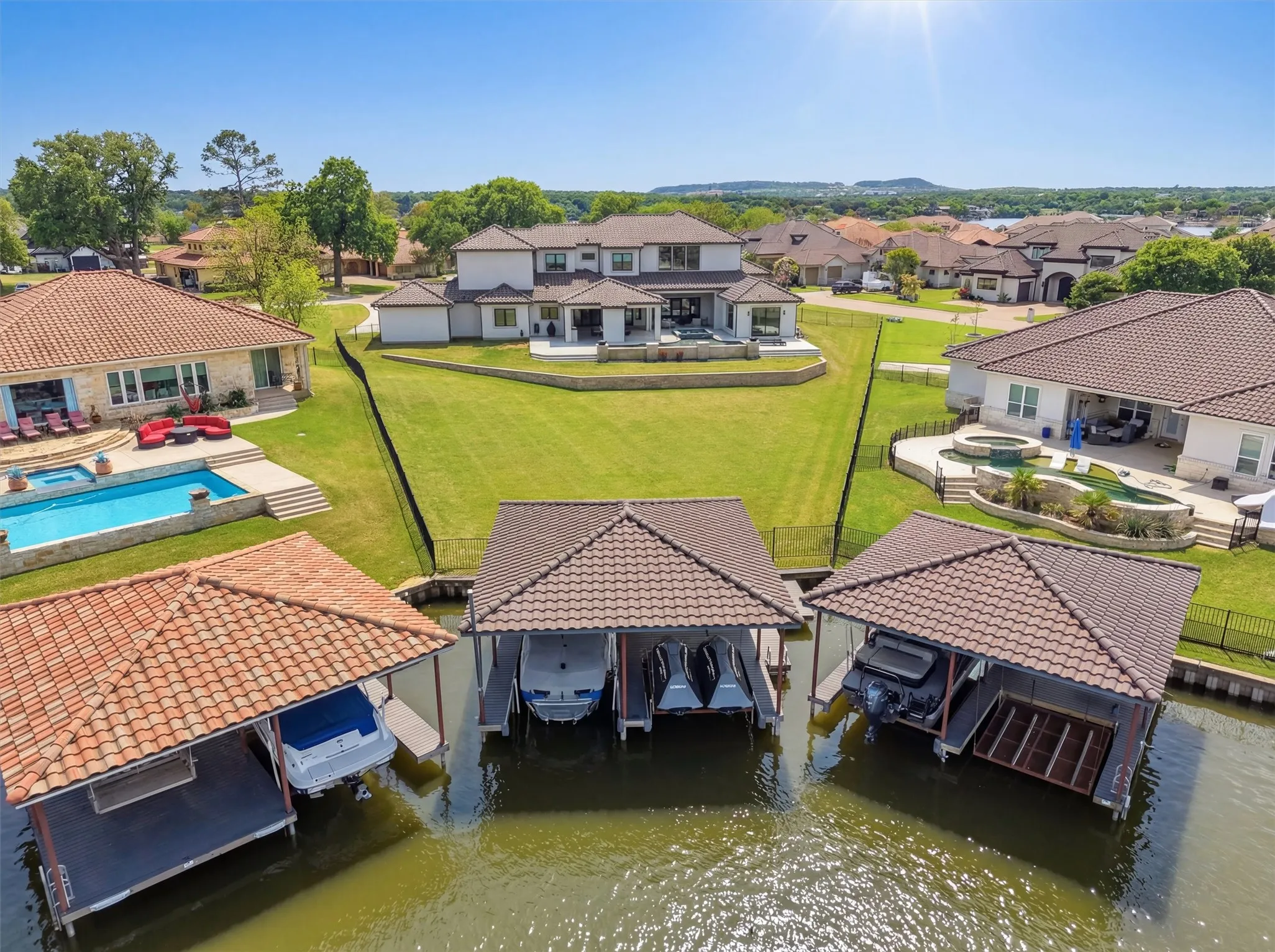 Protected Dock area featuring boat lift, a patio, a pool with connected hot tub, and a canal view. Keeps boat safe from wake boats on mainbody.