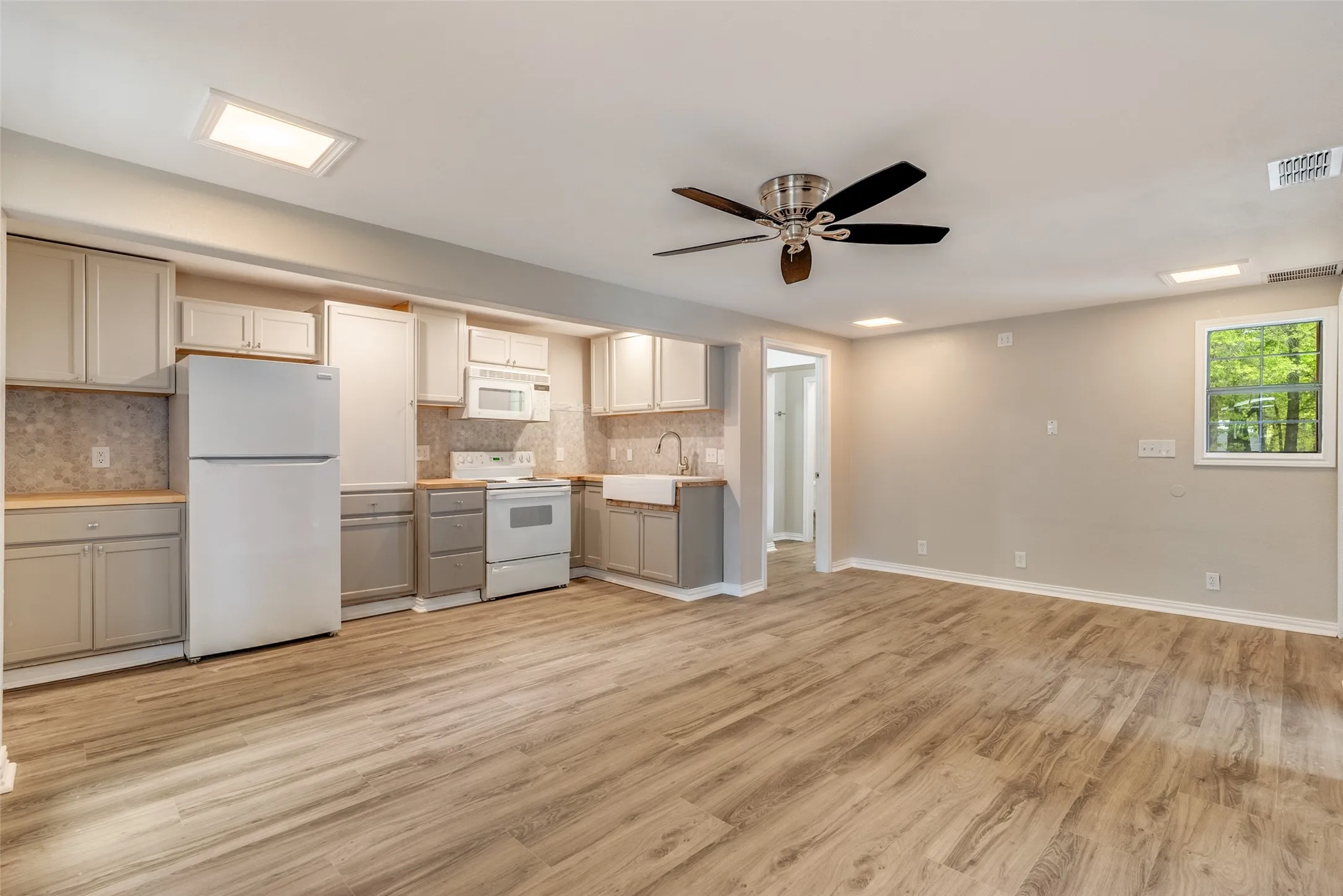 Kitchen featuring white appliances, ceiling fan, backsplash, light wood-style floors, and gray cabinets