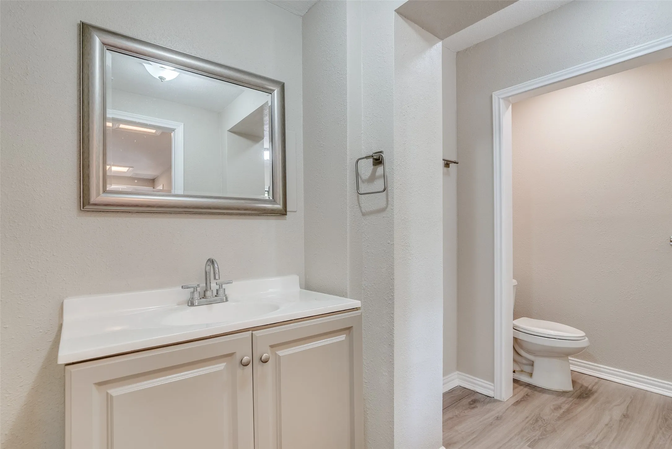 Bathroom with vanity, light wood-style floors, and a textured wall