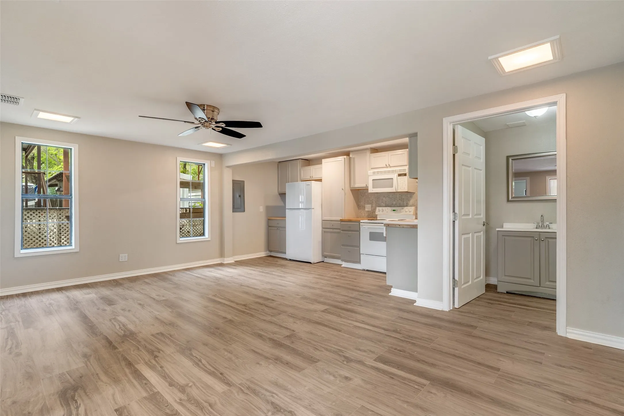 Unfurnished living room featuring ceiling fan, plenty of natural light, light wood-type flooring, and electric panel