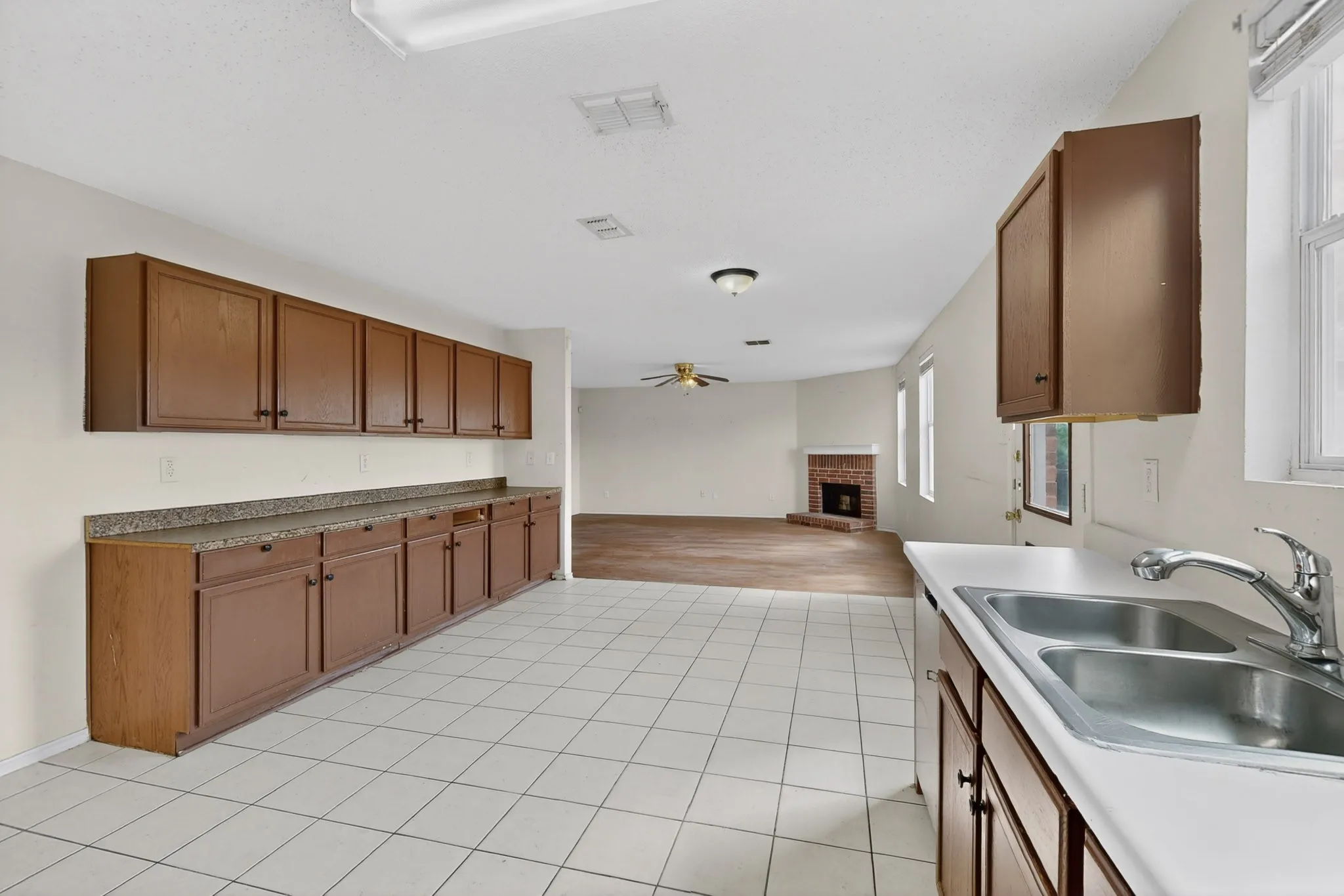 Kitchen featuring open floor plan, a brick fireplace, wood finish cabinetry, and a ceiling fan