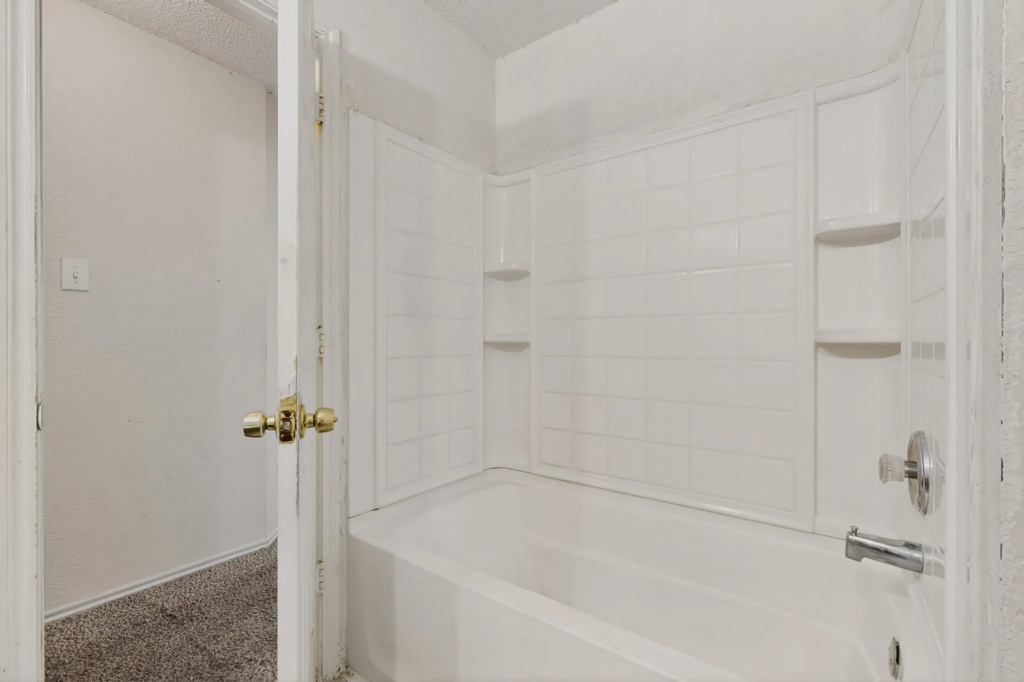 Bathroom with carpet, washtub / shower combination, a textured wall, and a textured ceiling