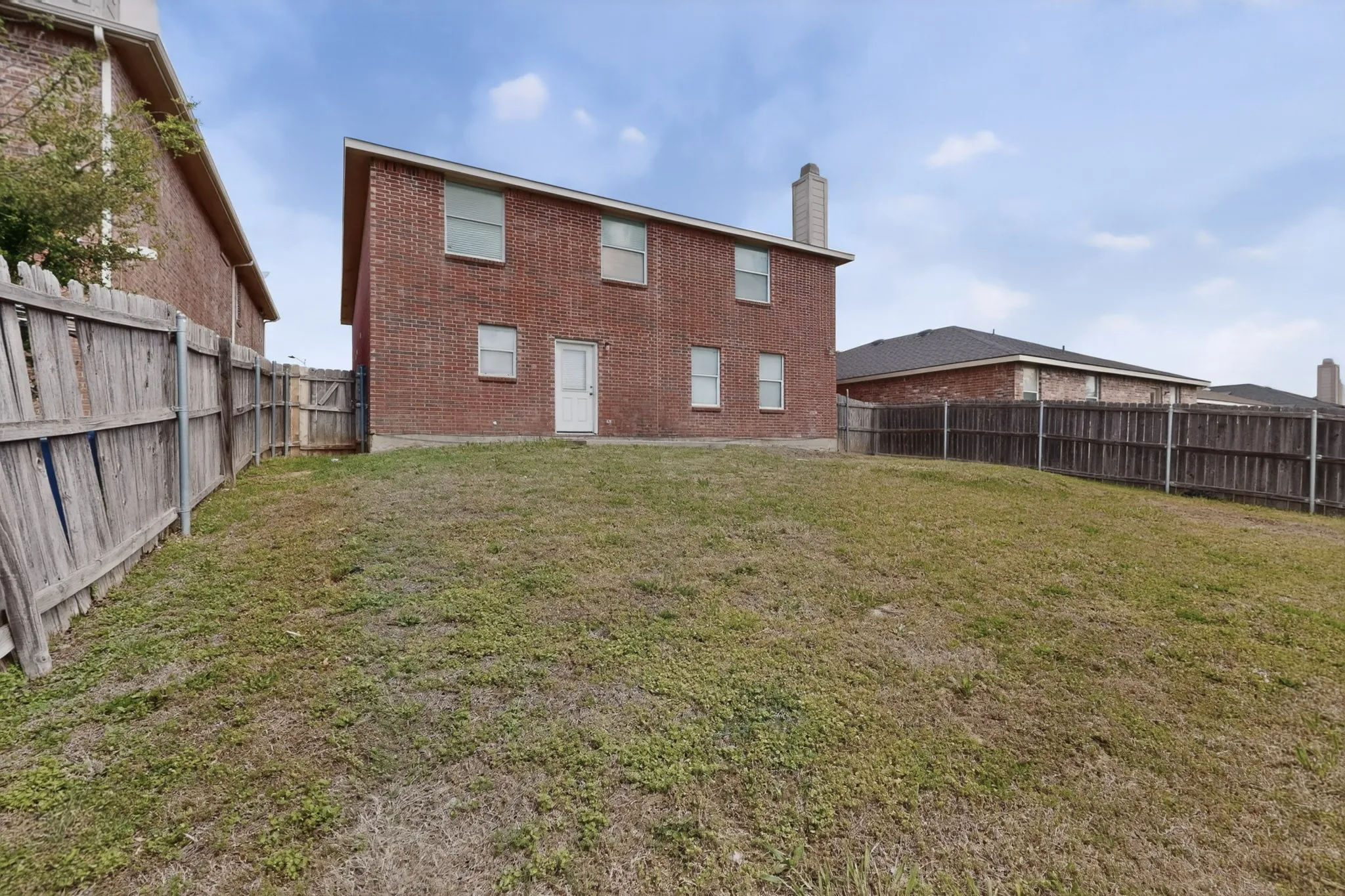 Rear view of house with a chimney, a fenced backyard, and brick siding