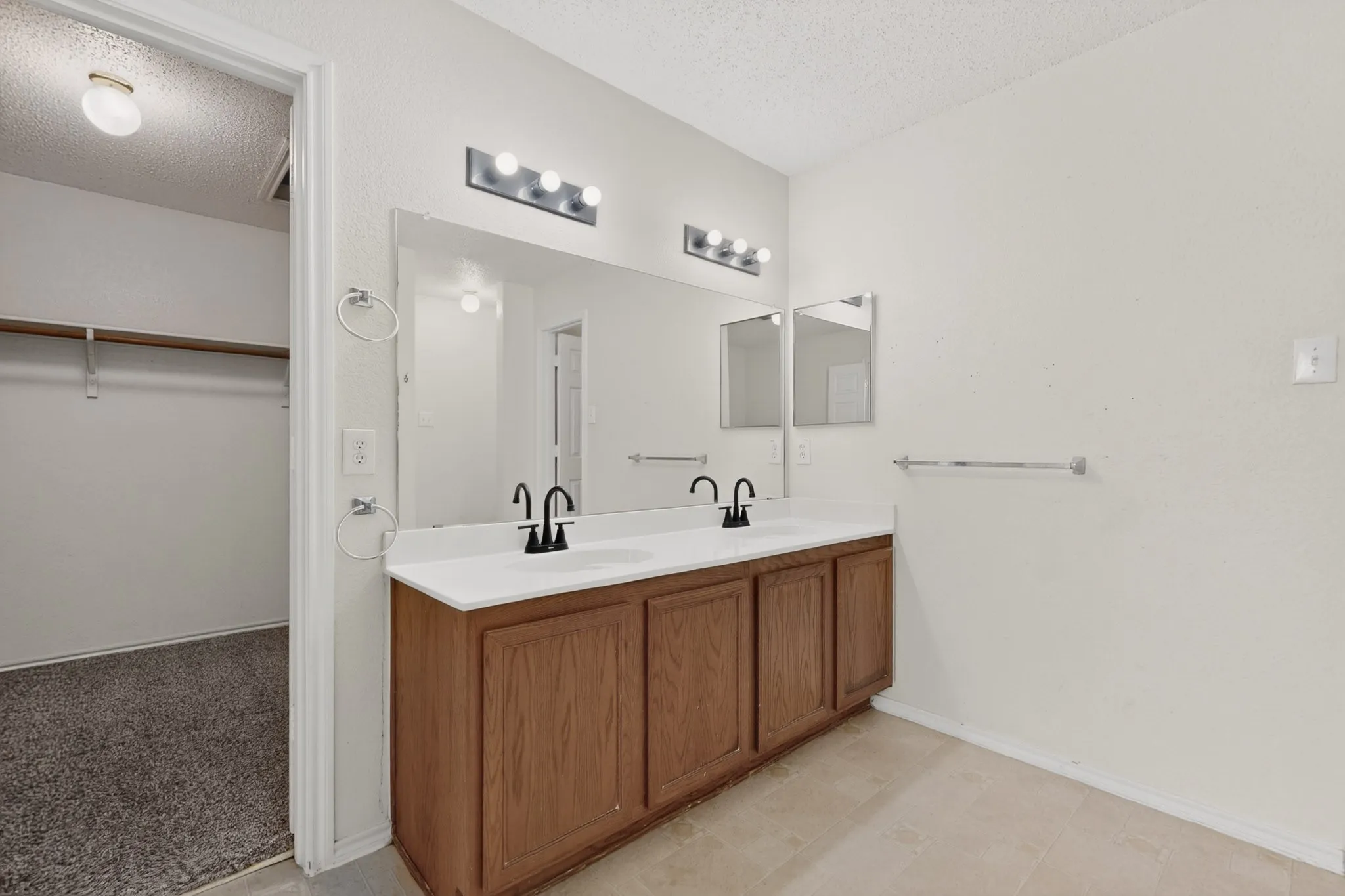 Full bathroom with a spacious closet, double vanity, and a textured ceiling