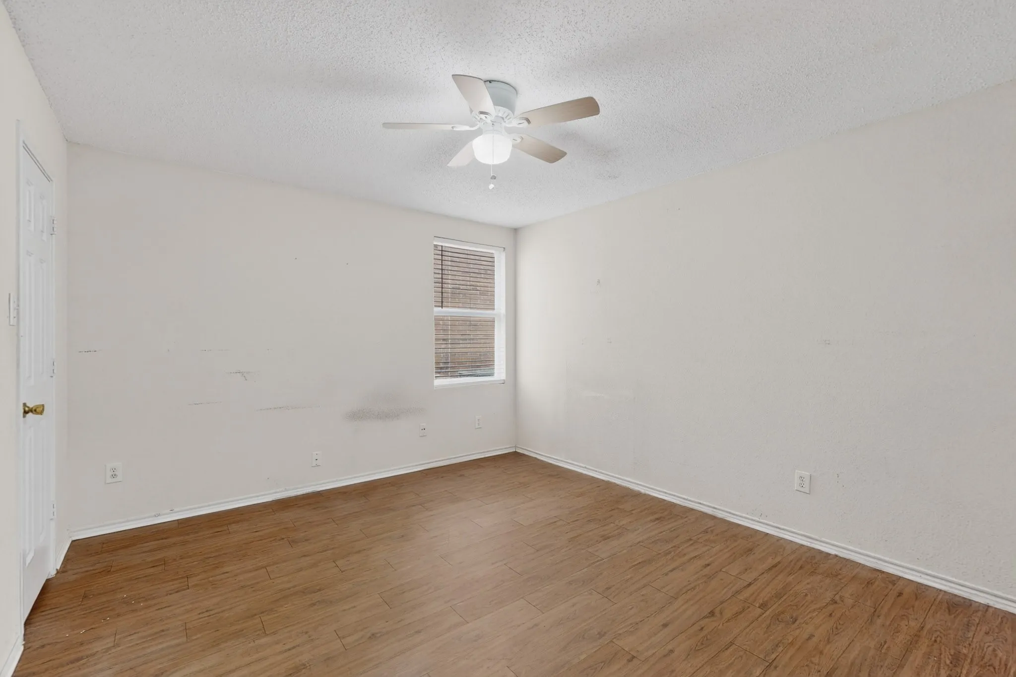 Empty room featuring wood finished floors, a textured ceiling, and ceiling fan