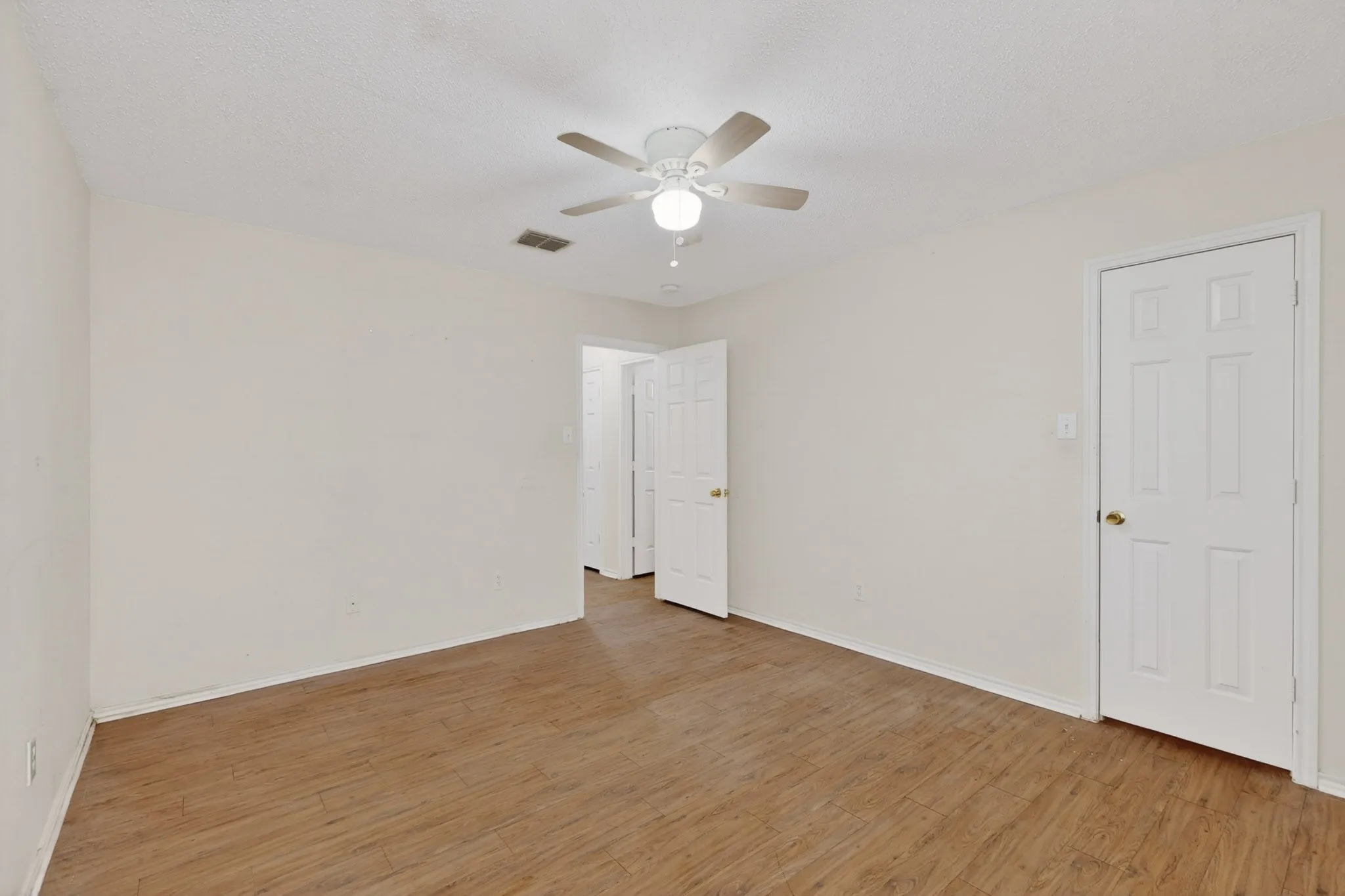 Spare room featuring light wood-style floors, a ceiling fan, and a textured ceiling