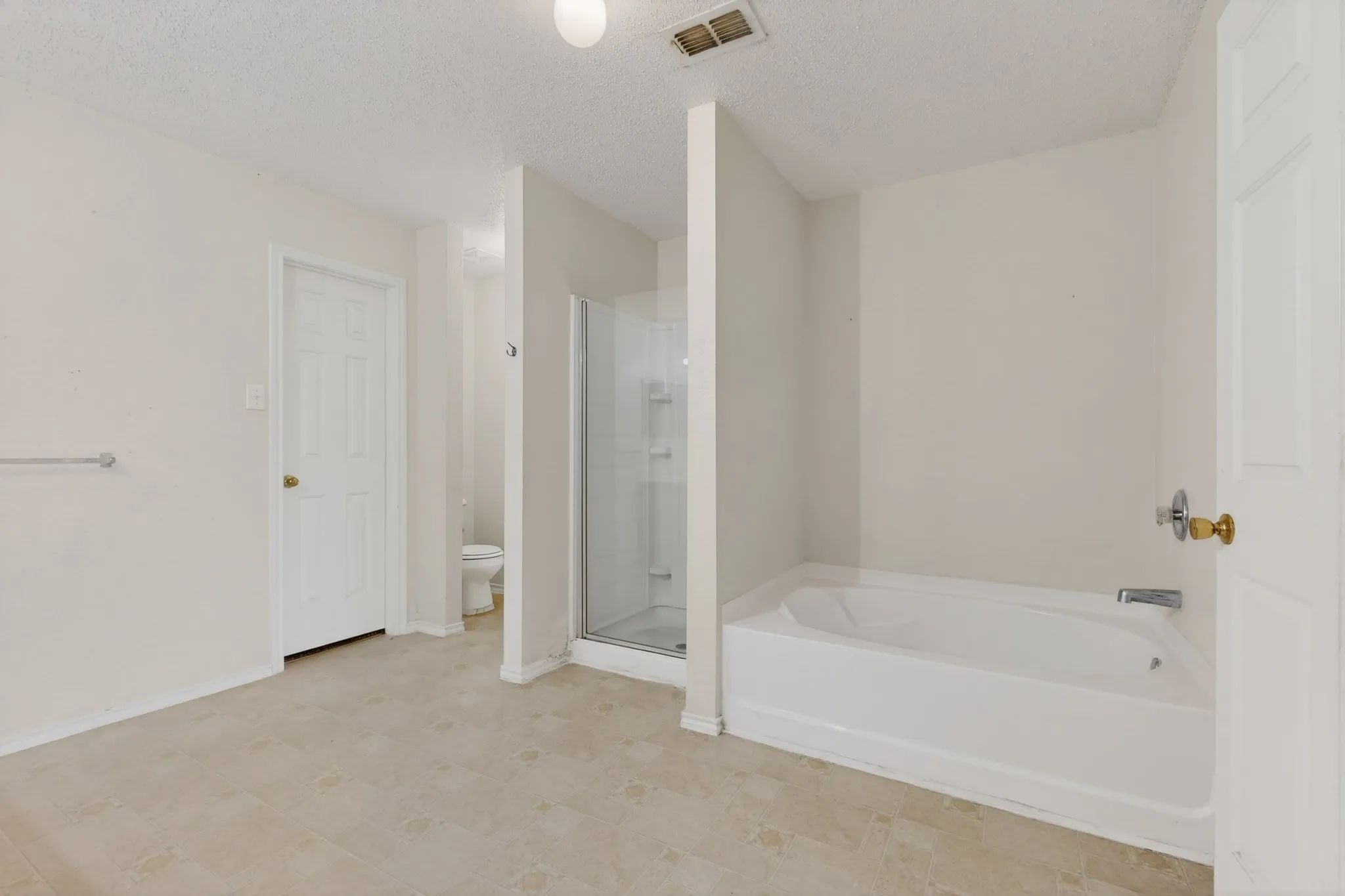 Full bath with a textured ceiling, a stall shower, and a bath