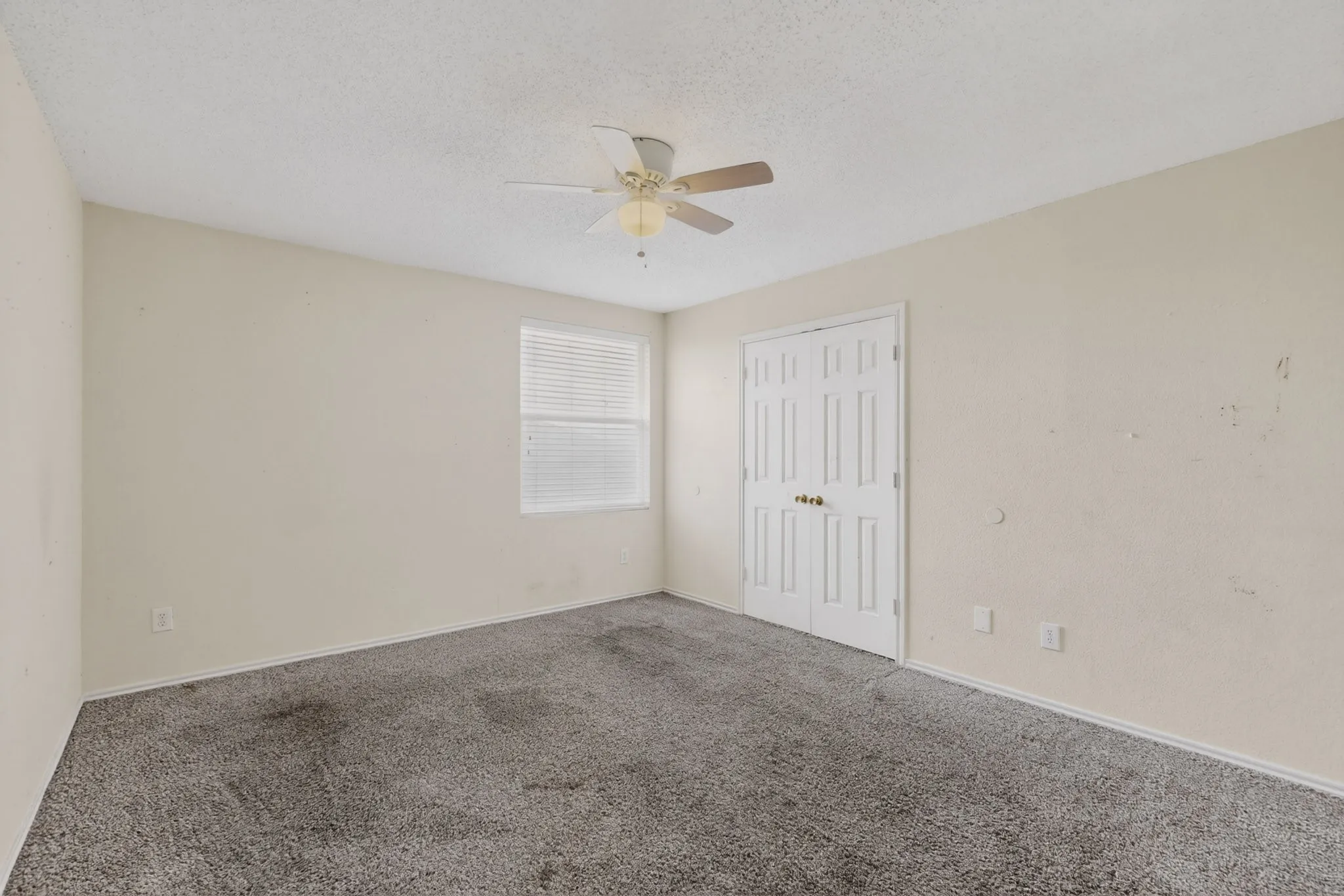 Unfurnished bedroom with carpet, a textured ceiling, a closet, and ceiling fan
