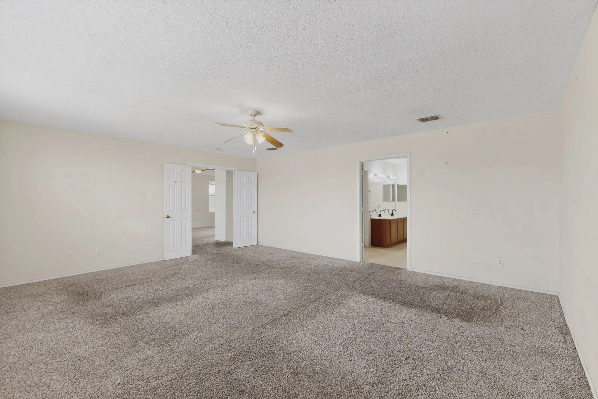 Unfurnished room featuring light carpet, ceiling fan, and a textured​​‌​​​​‌​​‌‌​‌‌​​​‌‌​‌​‌​‌​​​‌​​ ceiling