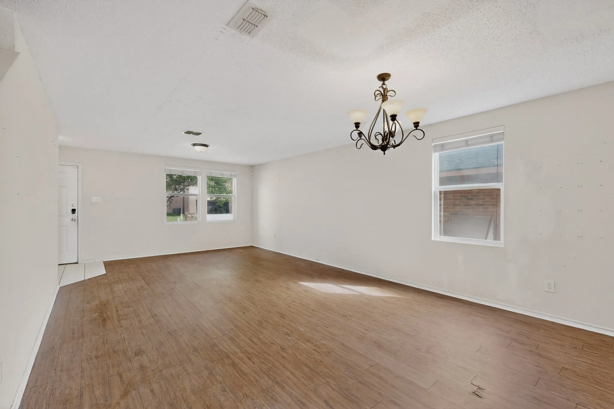 Unfurnished room featuring hanging lights, wood finished floors, and a textured ceiling