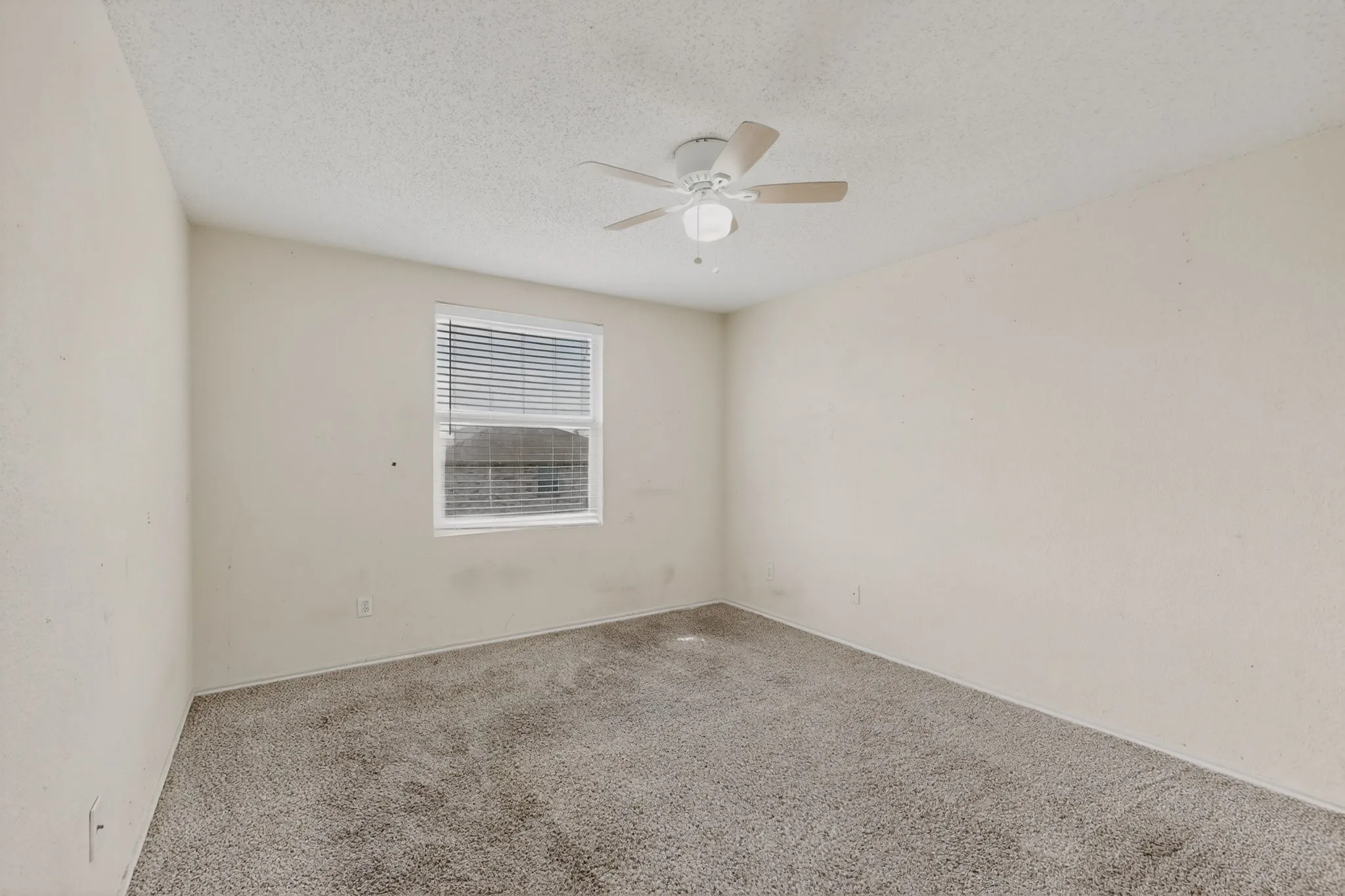 Carpeted empty room with a textured ceiling and ceiling fan