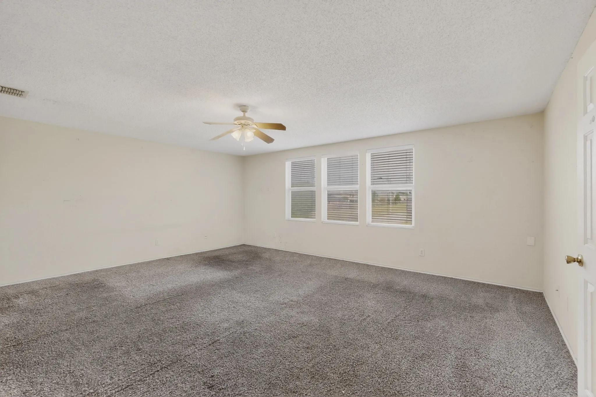 Carpeted spare room featuring a textured ceiling and ceiling fan