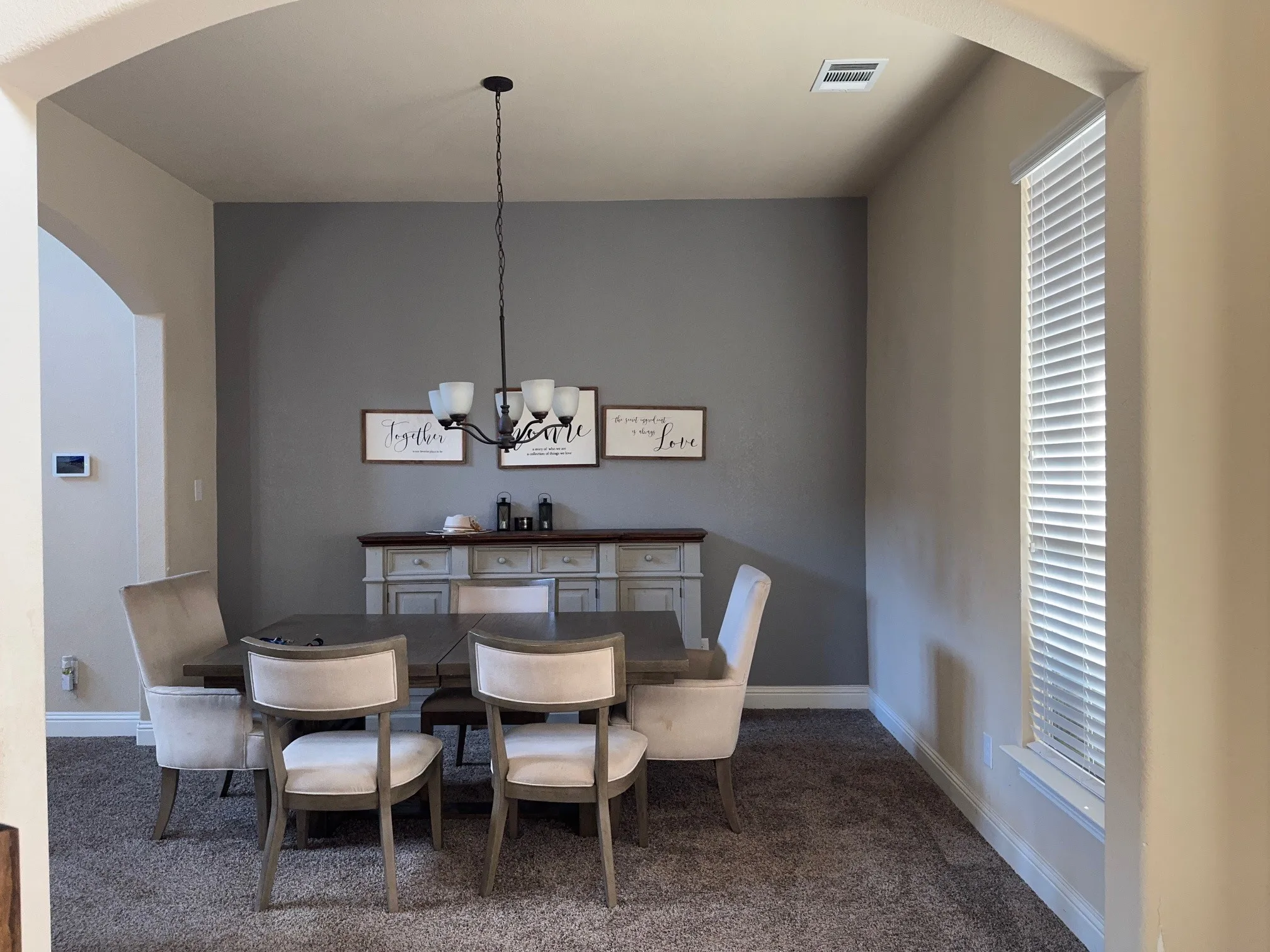 Archway entry to a carpeted room featuring a ceiling-mounted chandelier