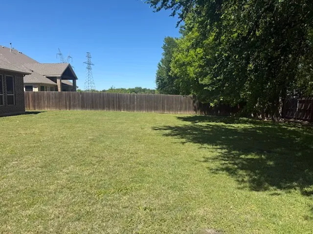 Expansive grassy yard area with a wood privacy fence
