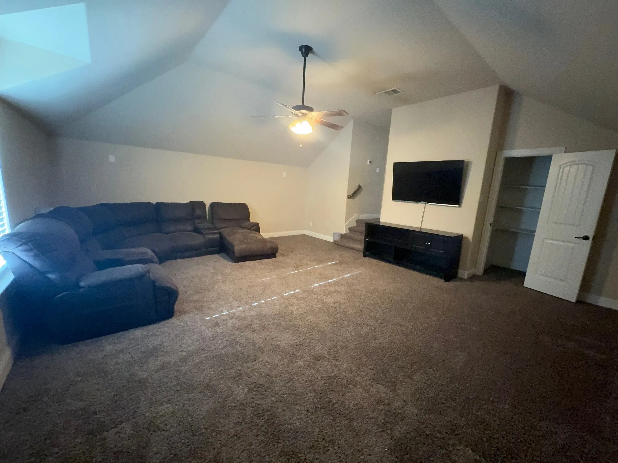 Spacious bonus room featuring vaulted ceilings, plush carpet flooring, a ceiling fan with integrated lighting, and a storage closet with shelving