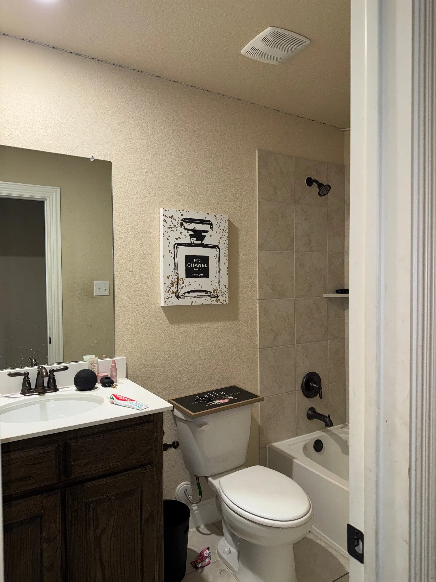 Bathroom featuring a wood-finish vanity with a white countertop and integrated sink, oil-rubbed bronze faucet, and a tiled shower-tub combination with matching fixtures