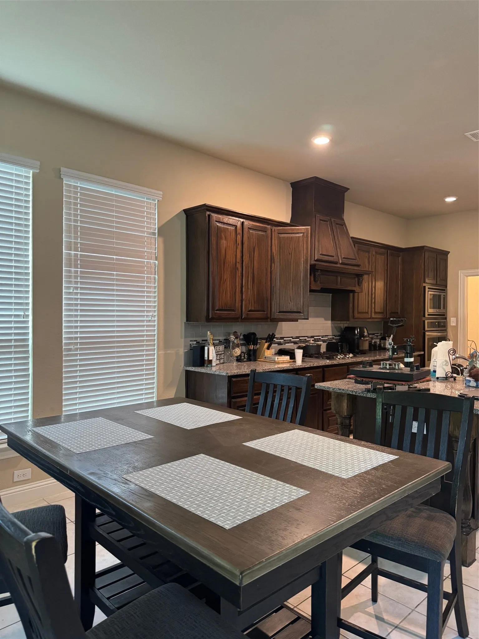 Kitchen with dark wood cabinetry, granite countertops, and a built-in range hood