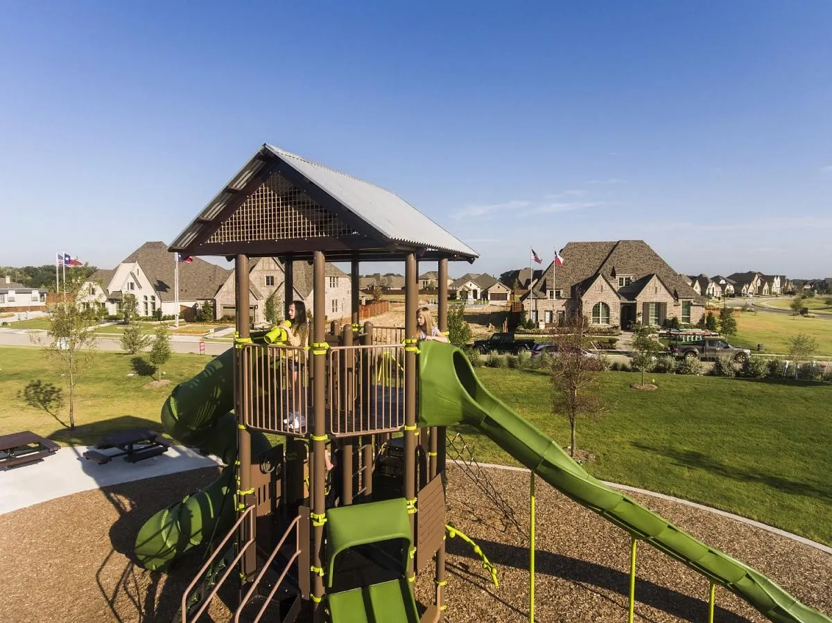 Community playground featuring multiple slides, covered tower, and soft fall surfacing