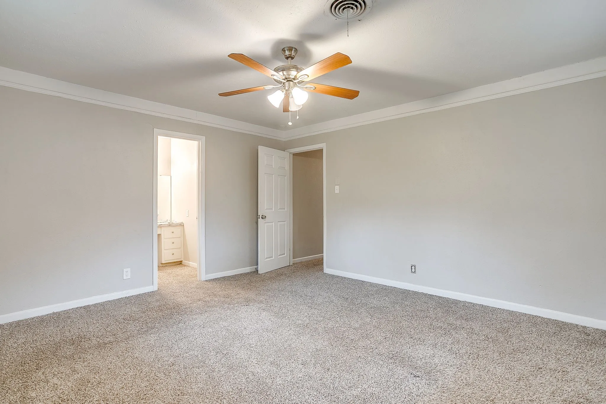 Spacious room featuring neutral carpet flooring, light gray wall paint, and white crown molding
