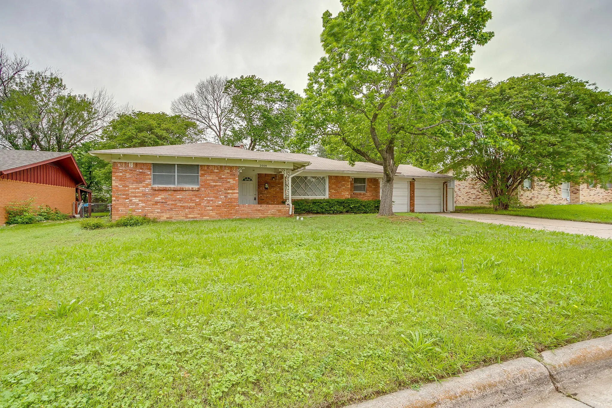 Brick exterior with a covered porch, established front yard, and two-car garage