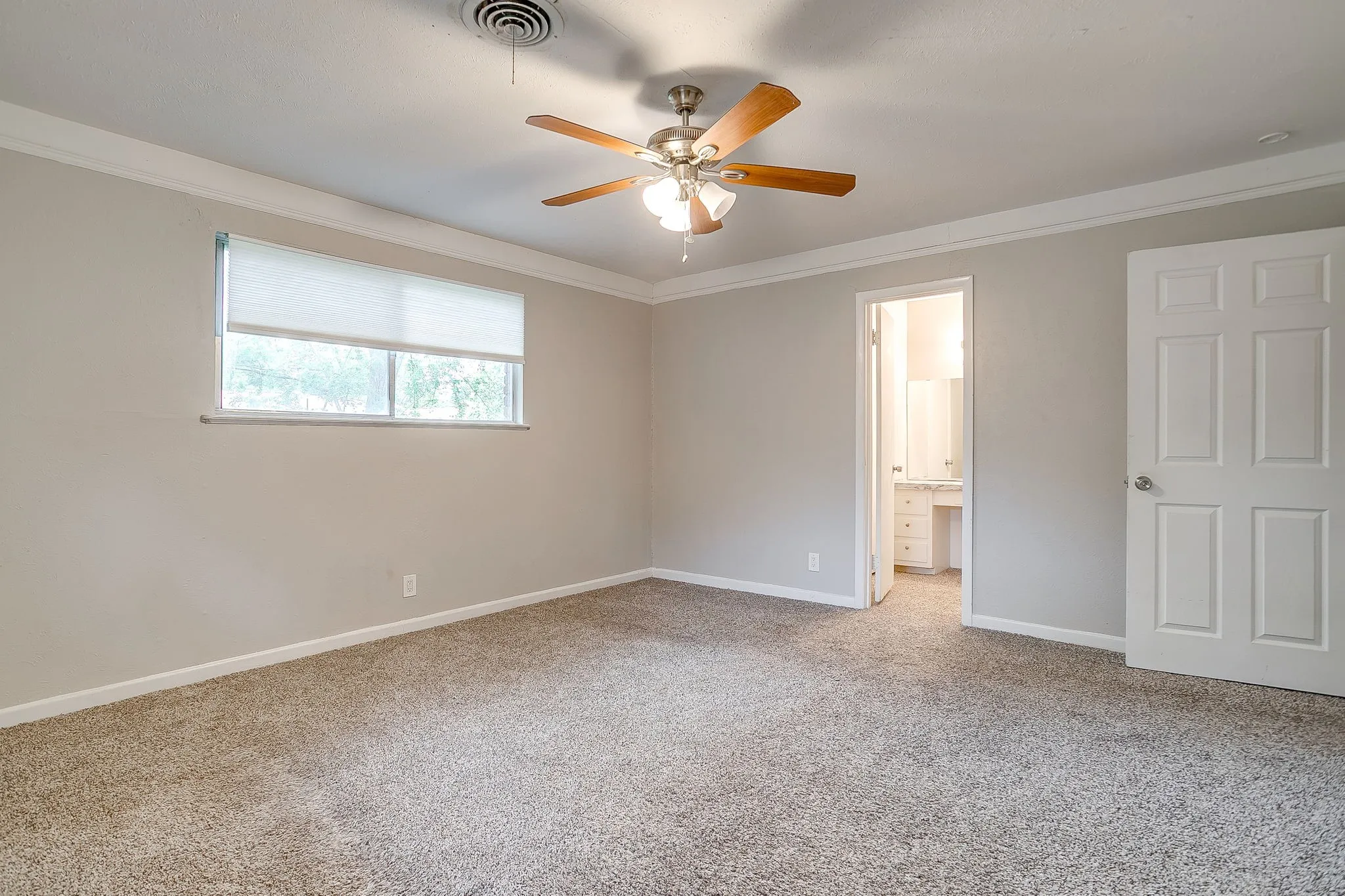 Carpeted room featuring a ceiling fan, crown molding, and a window with blinds