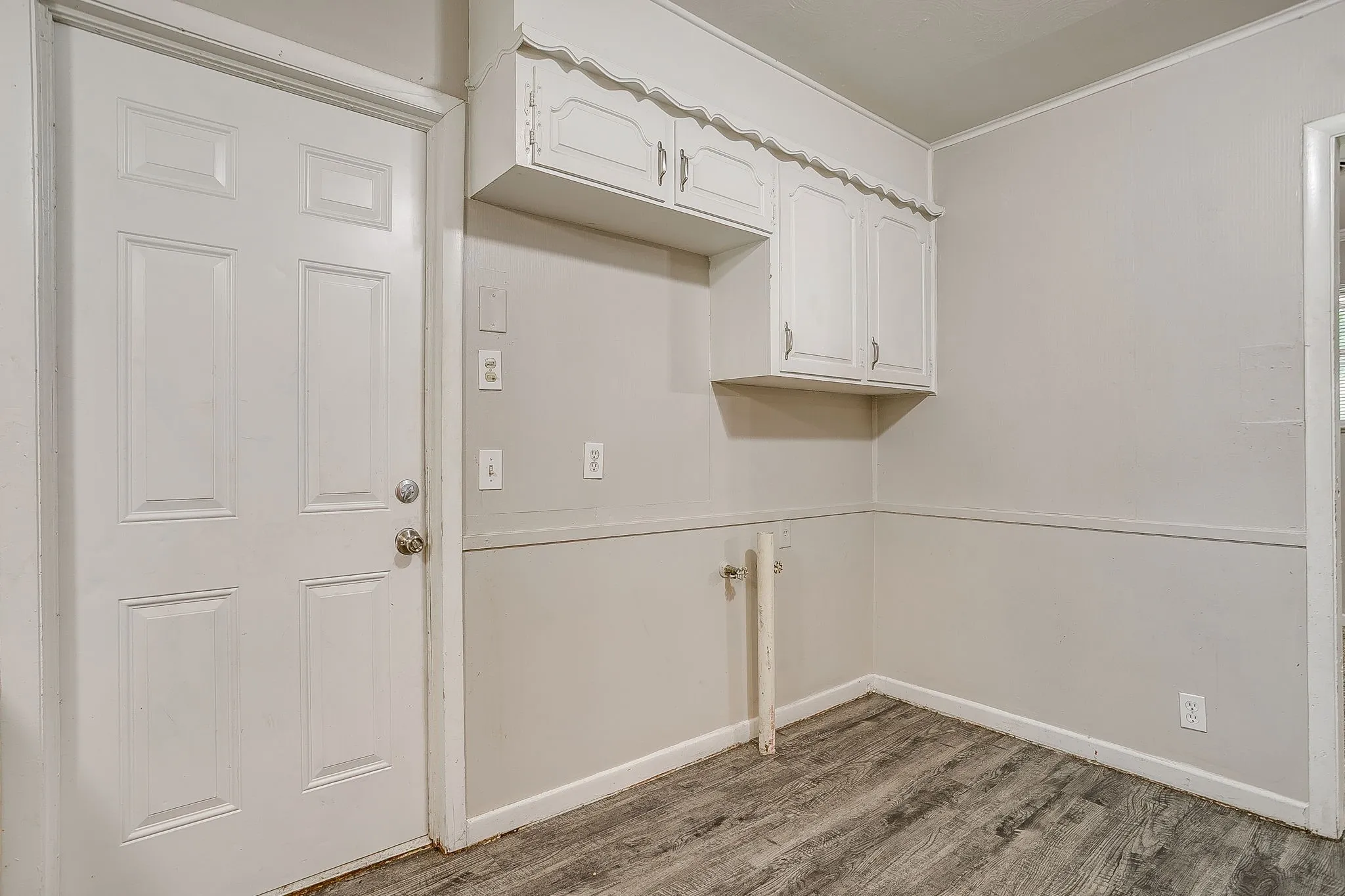 Utility area featuring wall-mounted cabinetry, wood-finish flooring, and a paneled door