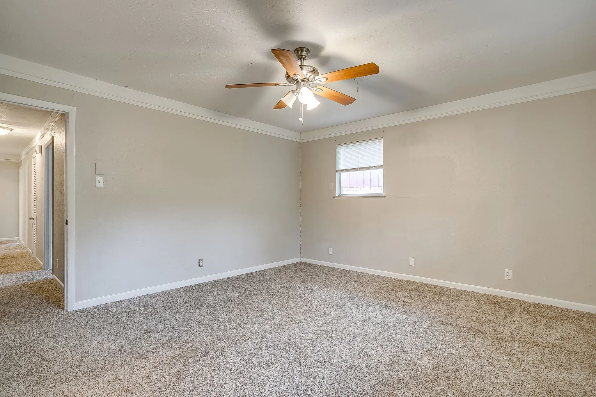 Carpeted room with a ceiling fan light fixture, crown molding, and a window with blinds