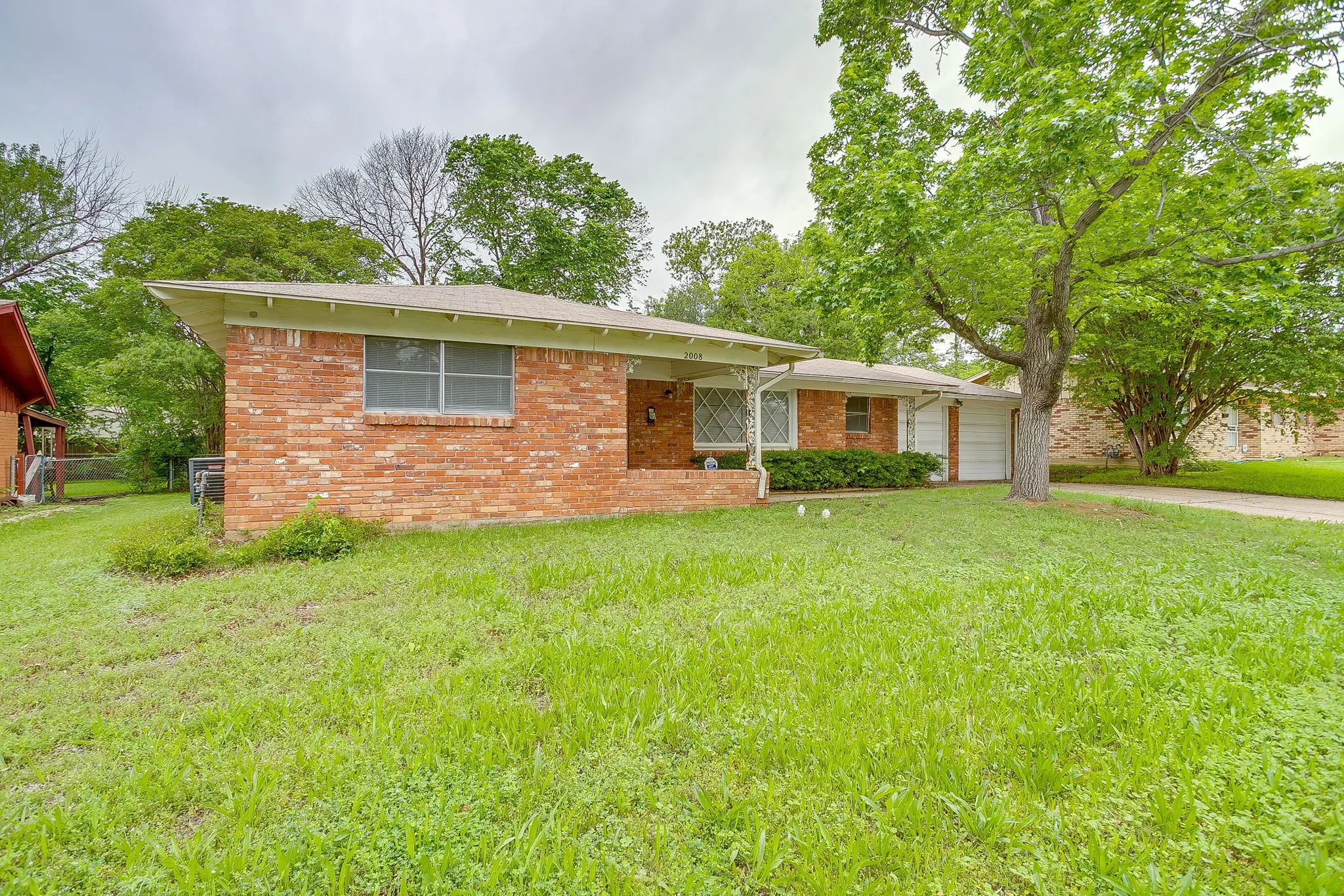 Red brick exterior with white trim, featuring a partial covered porch and an attached garage with a white door