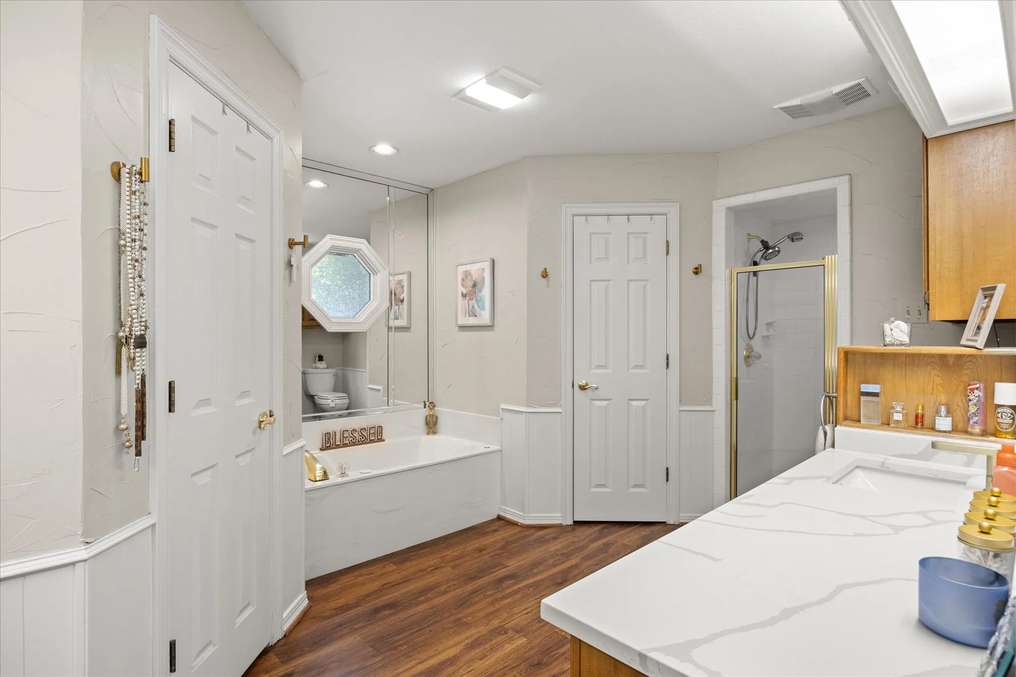 Bathroom with wainscoting, a shower stall, dark wood-style floors, vanity, and a bath